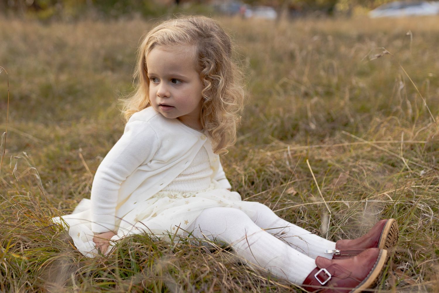 Little girl sitting in afield looking back Outdoor family session Macedon Ranges Melb Vic