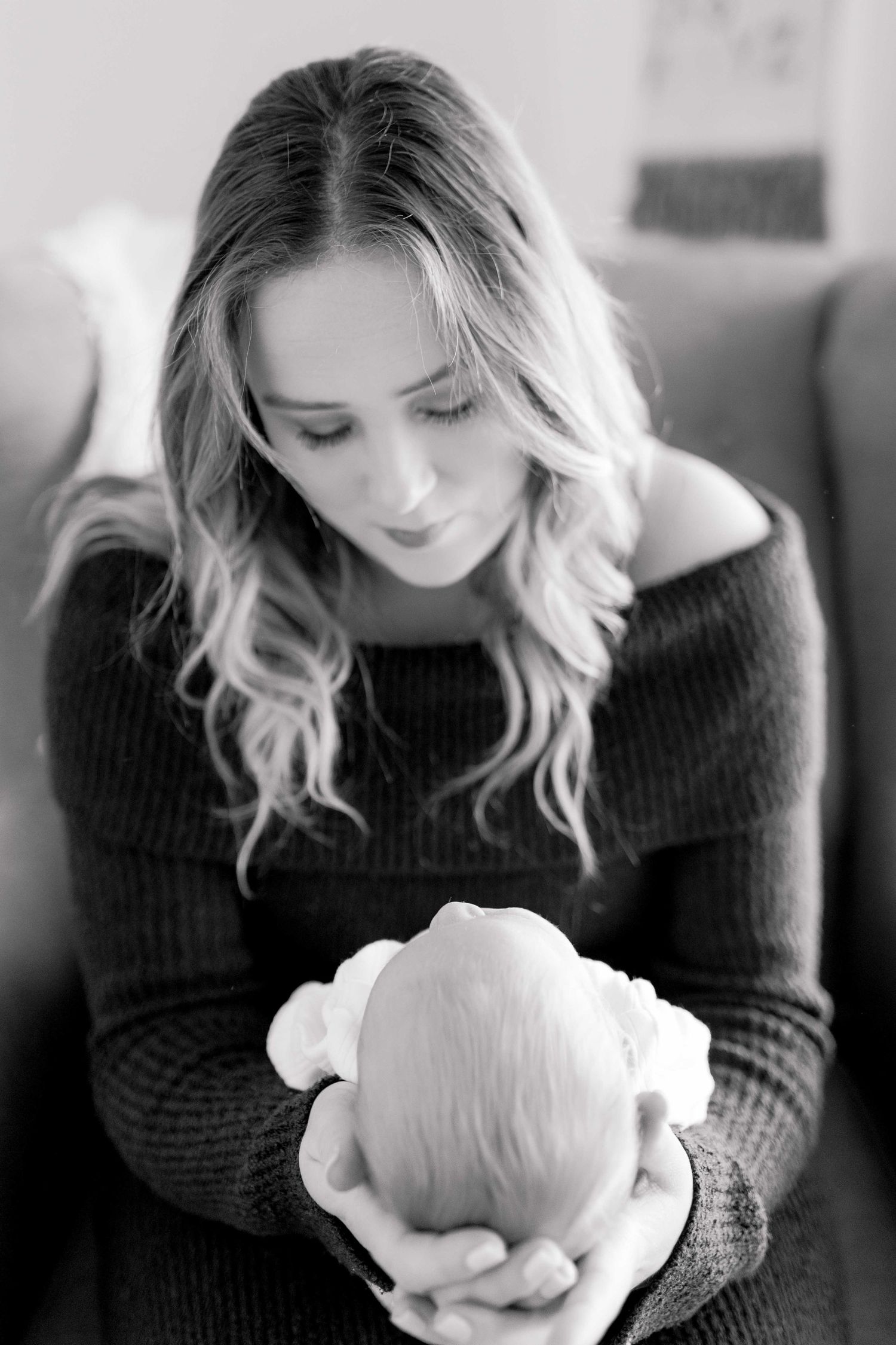 Mum holding newborn in her hands and her looking down at him