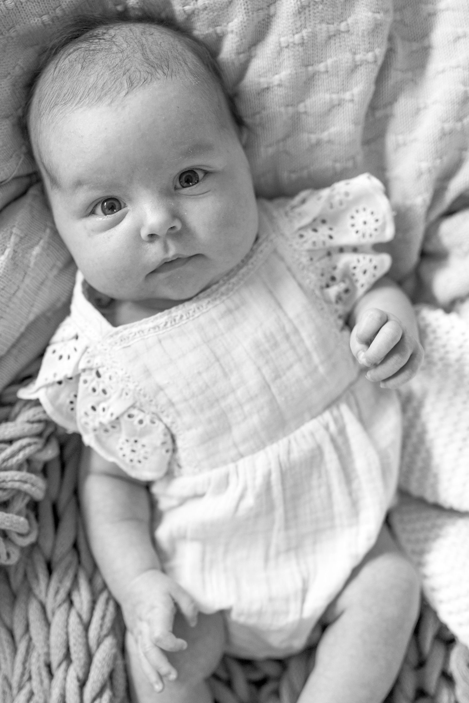 Newborn baby girl looking up at the camera surrounded by soft blankets Newborn photoshoot in Melbourne's West