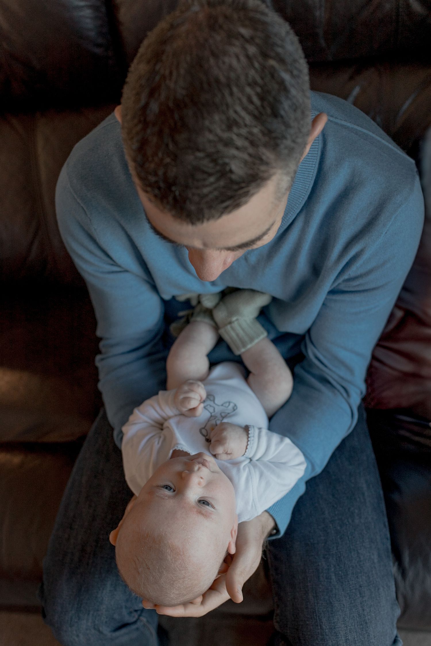 Dad holding newborn baby boy in his arms looking down at him At home newborn session Gisborne Melb Vic