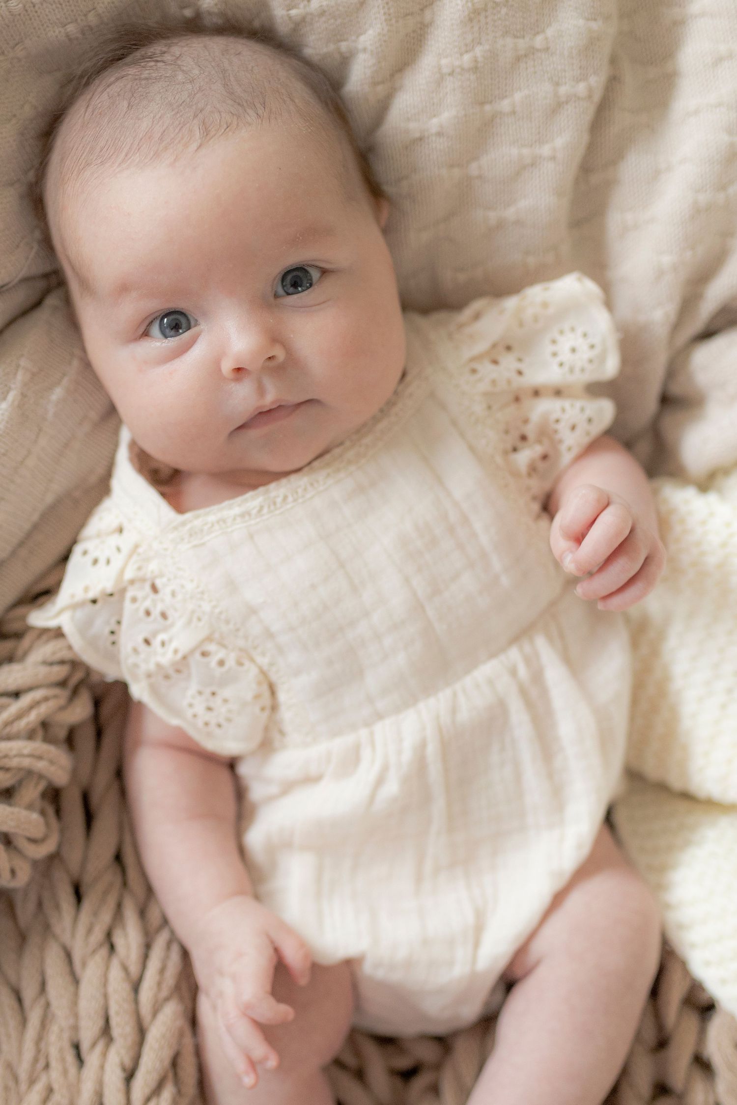 Newborn baby girl looking up at the camera surrounded by soft blankets Newborn photoshoot in Melbourne's West
