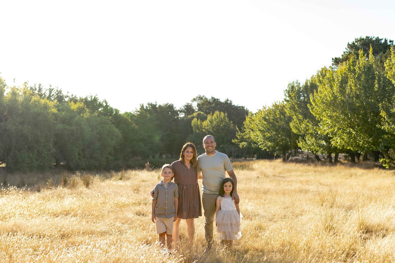 Family standing together in a field smiling comfortably Outdoor at home family session Gisborne Melb Vic