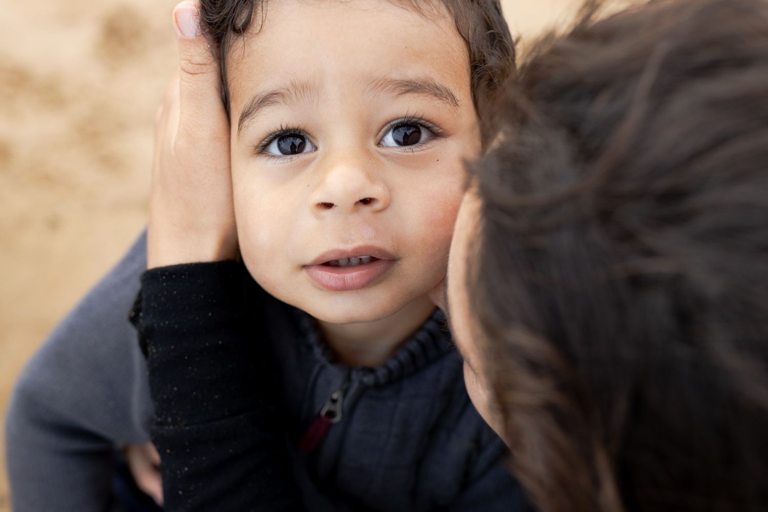 Toddler looking up from his mum's arm Outdoor family session Torquay