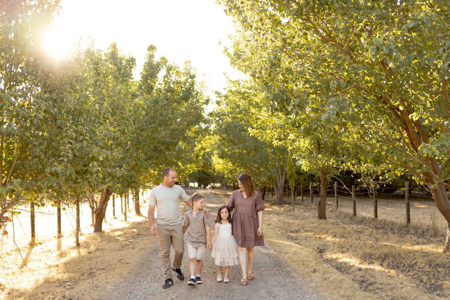 Family walking together in rows of trees comfortably  Outdoor at home family session Gisborne Melb Vic