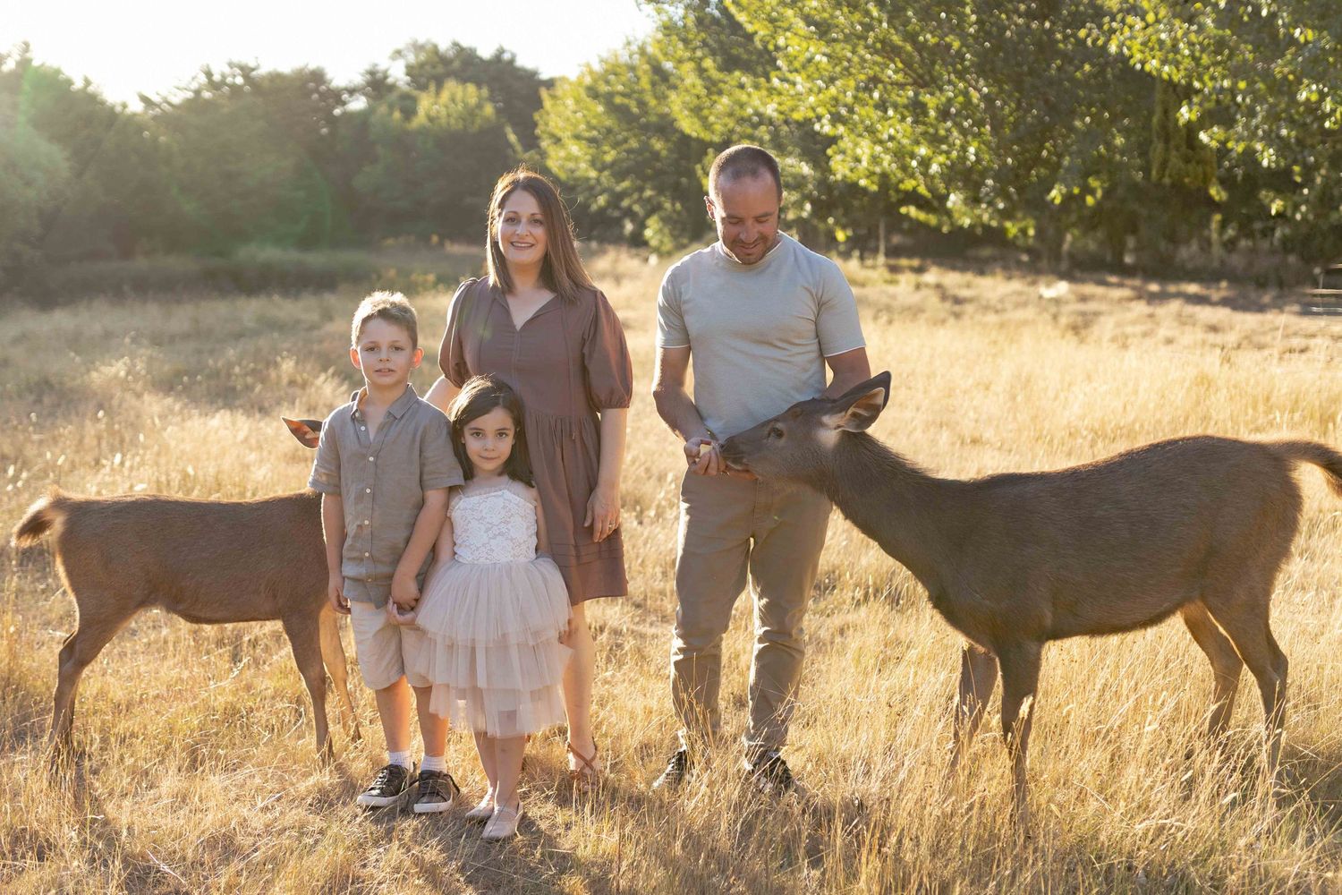 Family of four in the field standing with their pet deer Gisborne, Melb, Vic