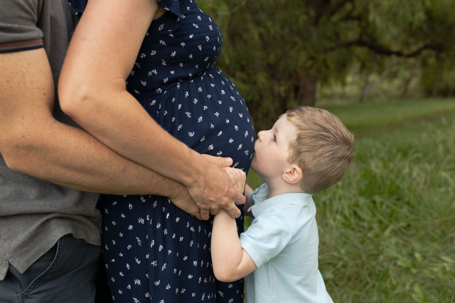 Maternity outdoor session parents hugging and toddler kissing mothers belly, Coburg Melb Vic