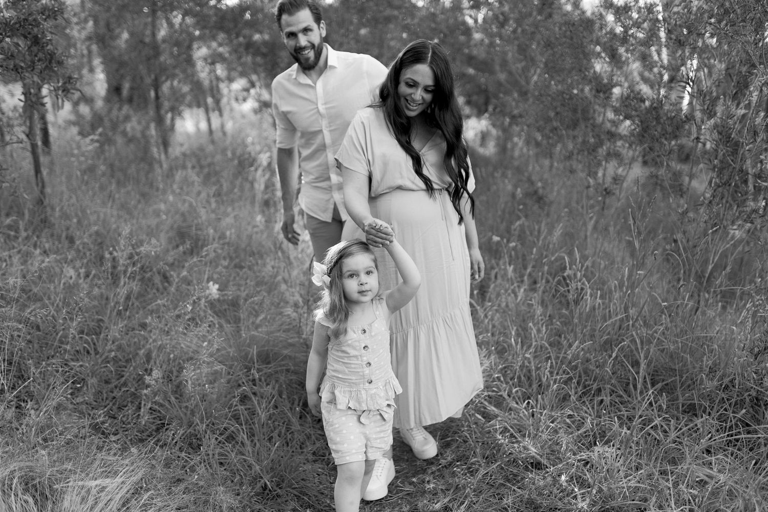 Little girl leading her parents through the bush Maternity outdoor session Sunshine North Melb Vic