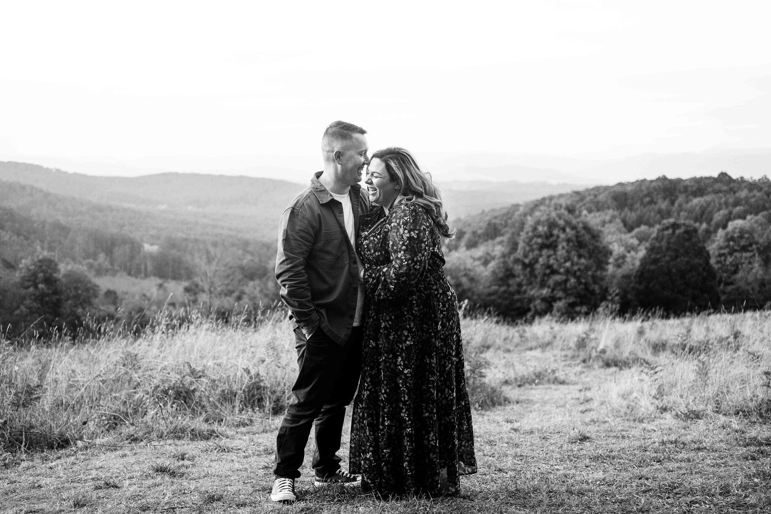 happy couple laughing family session on top of a hill