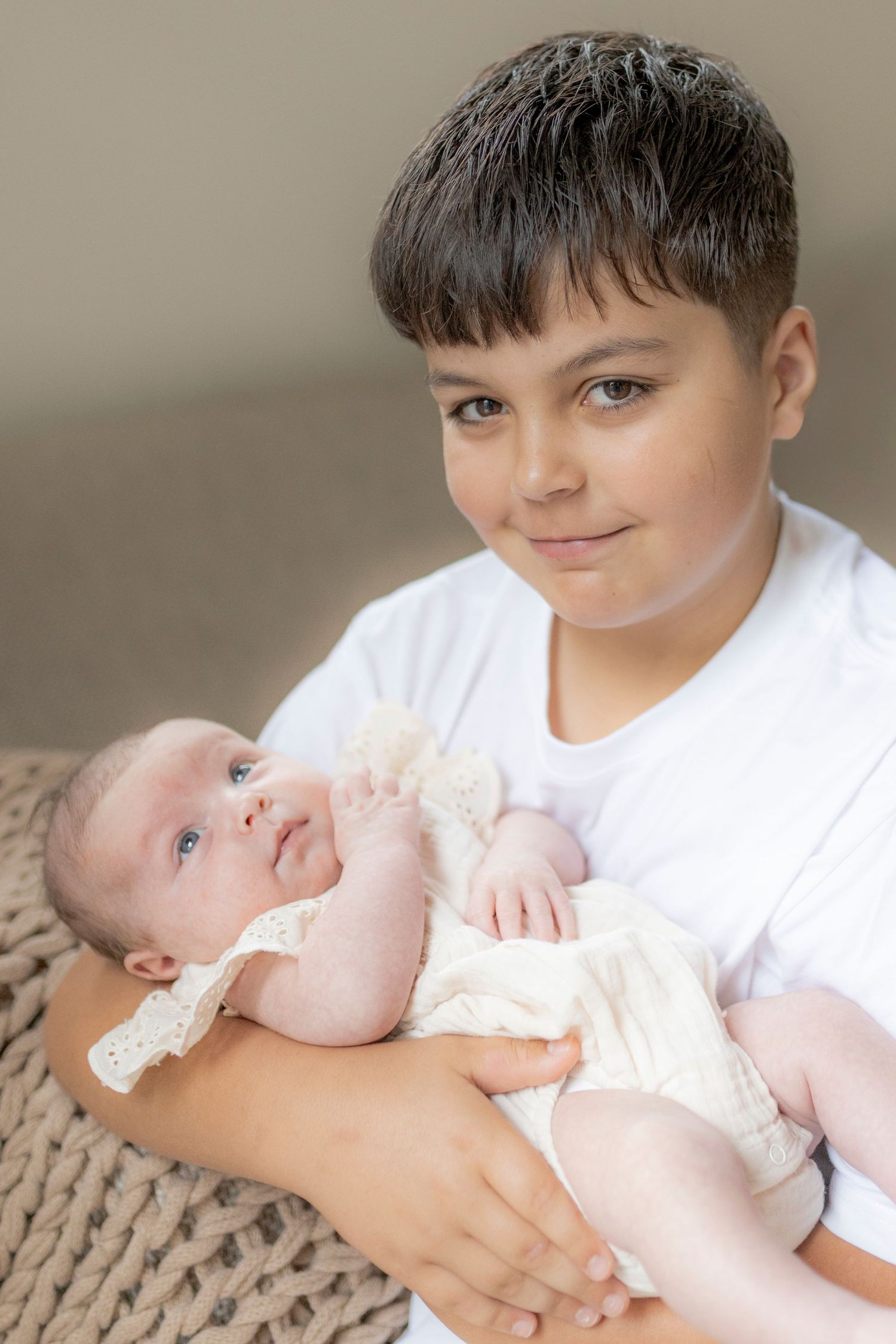 Big brother holding his baby sister and looking at the camera