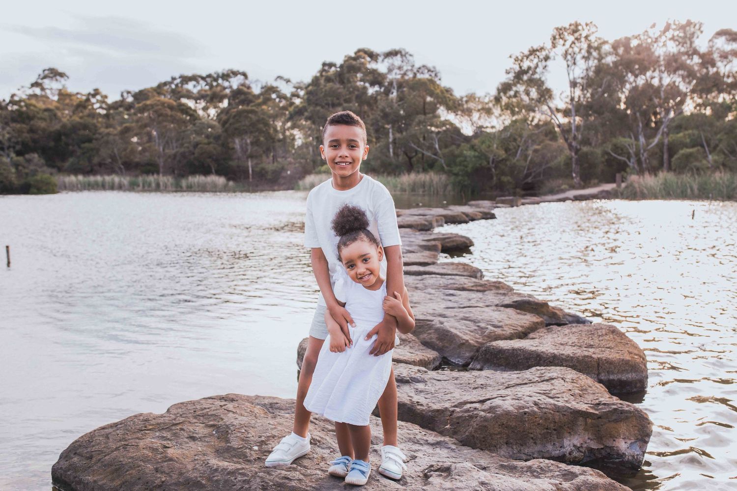 Brother and sister holding hands standing on the rocks across a lake outdoor family session Newport Lakes, Melbourne, Victoria