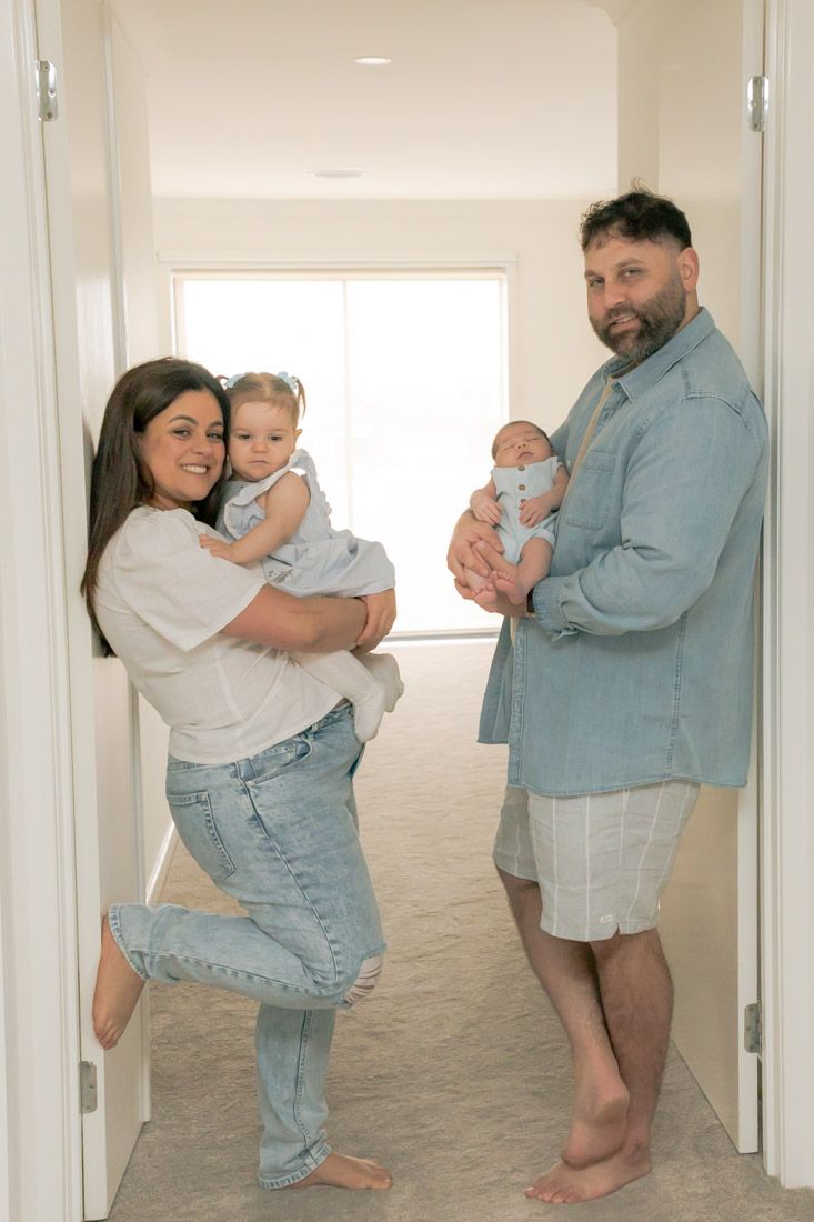 Parents leaning in the doorway and holding a child smiling