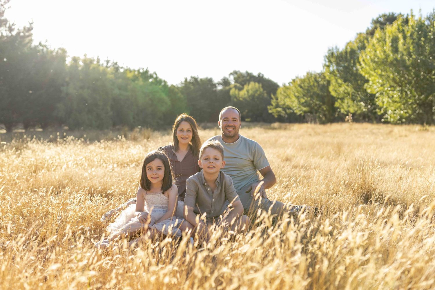 Family sitting together in a field smiling comfortably Outdoor at home family session Gisborne Melb Vic