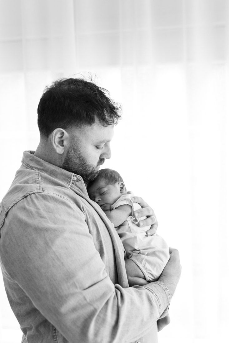 Black and white dad holding newborn to his chest