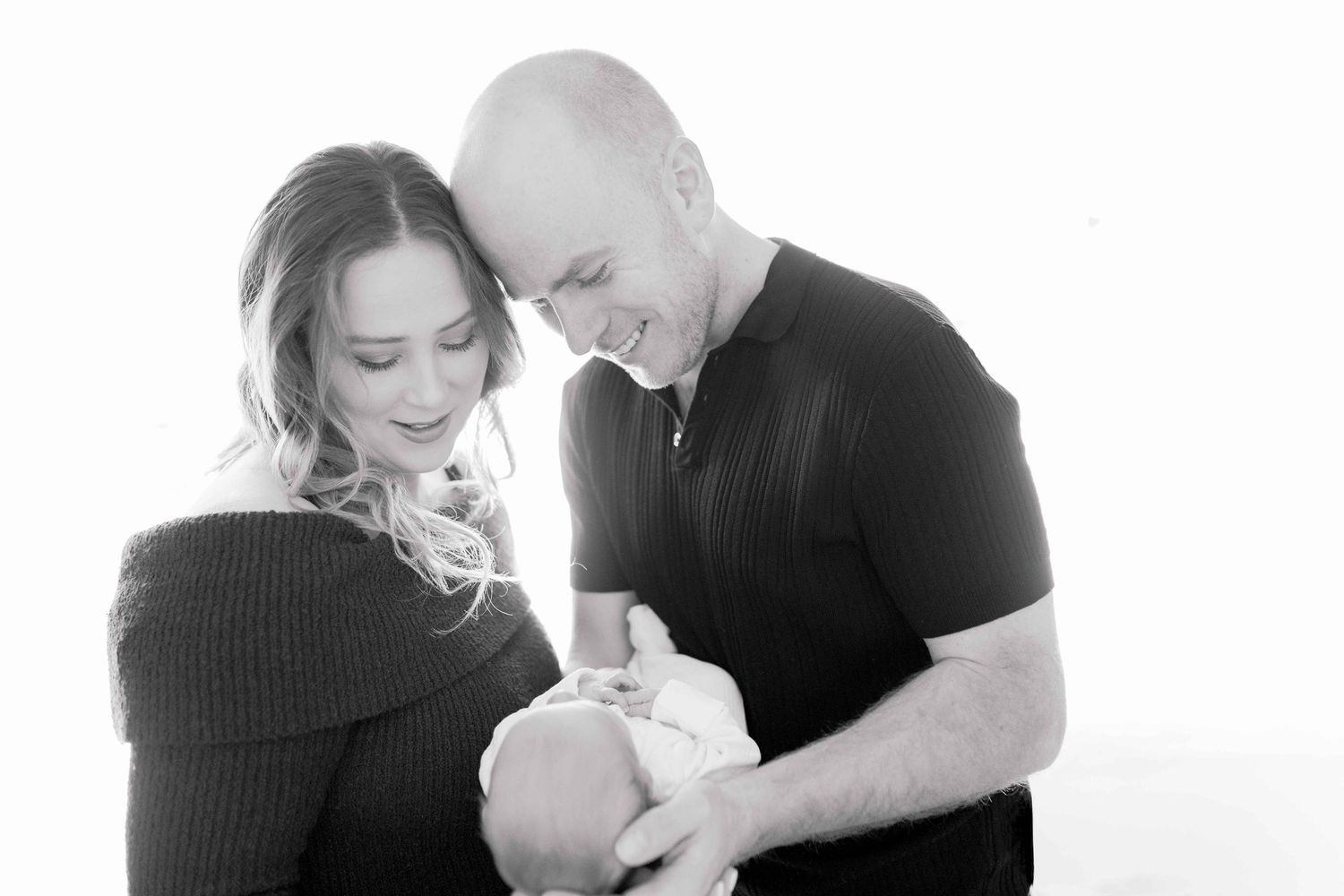 Mum and dad have their heads gently touching looking down at their baby boy newborn photoshoot Melton