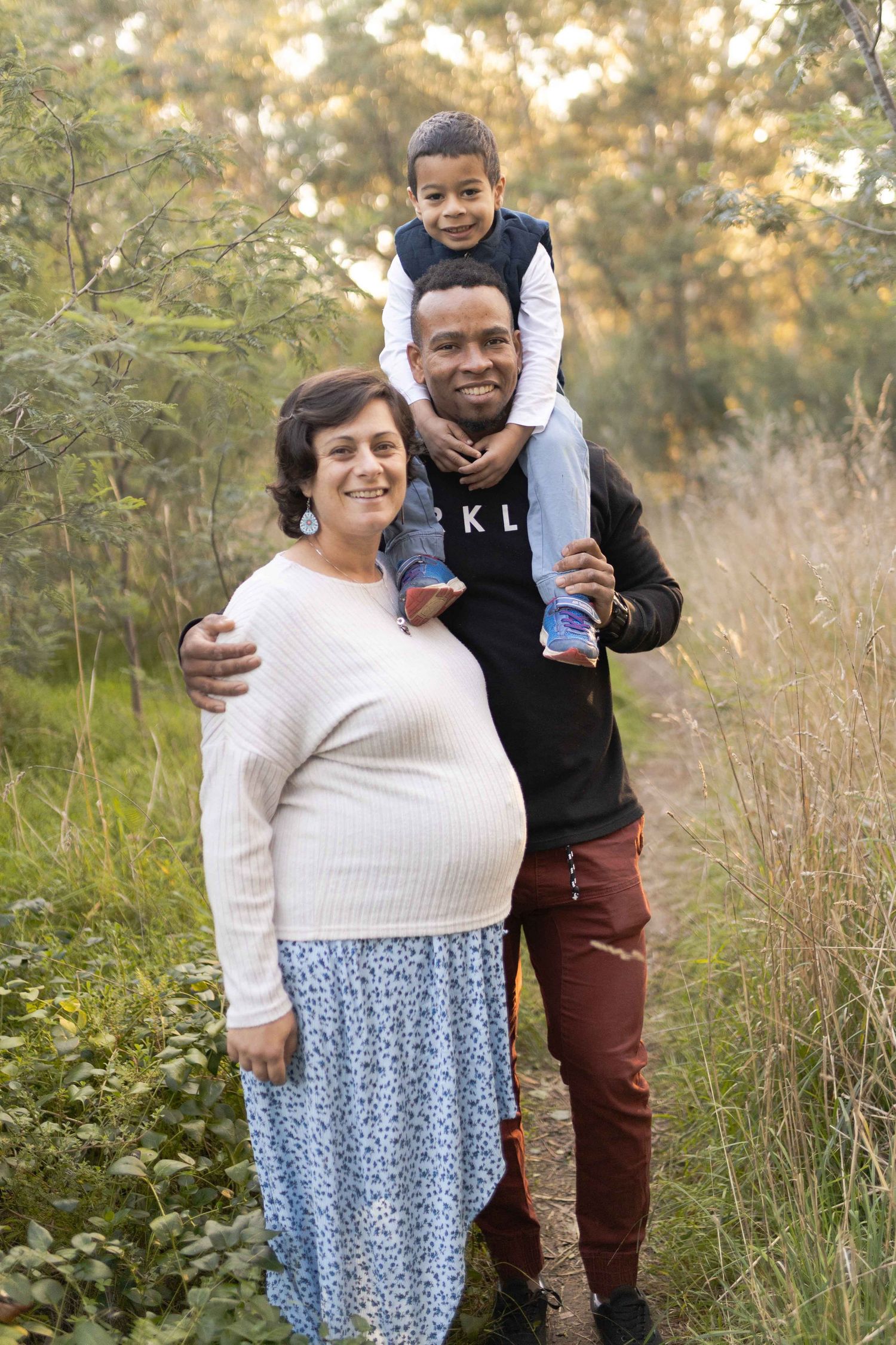 Family of three standing in the bushland, son on dad's shoulders Outdoor maternity session Sunshine Melb, Victoria