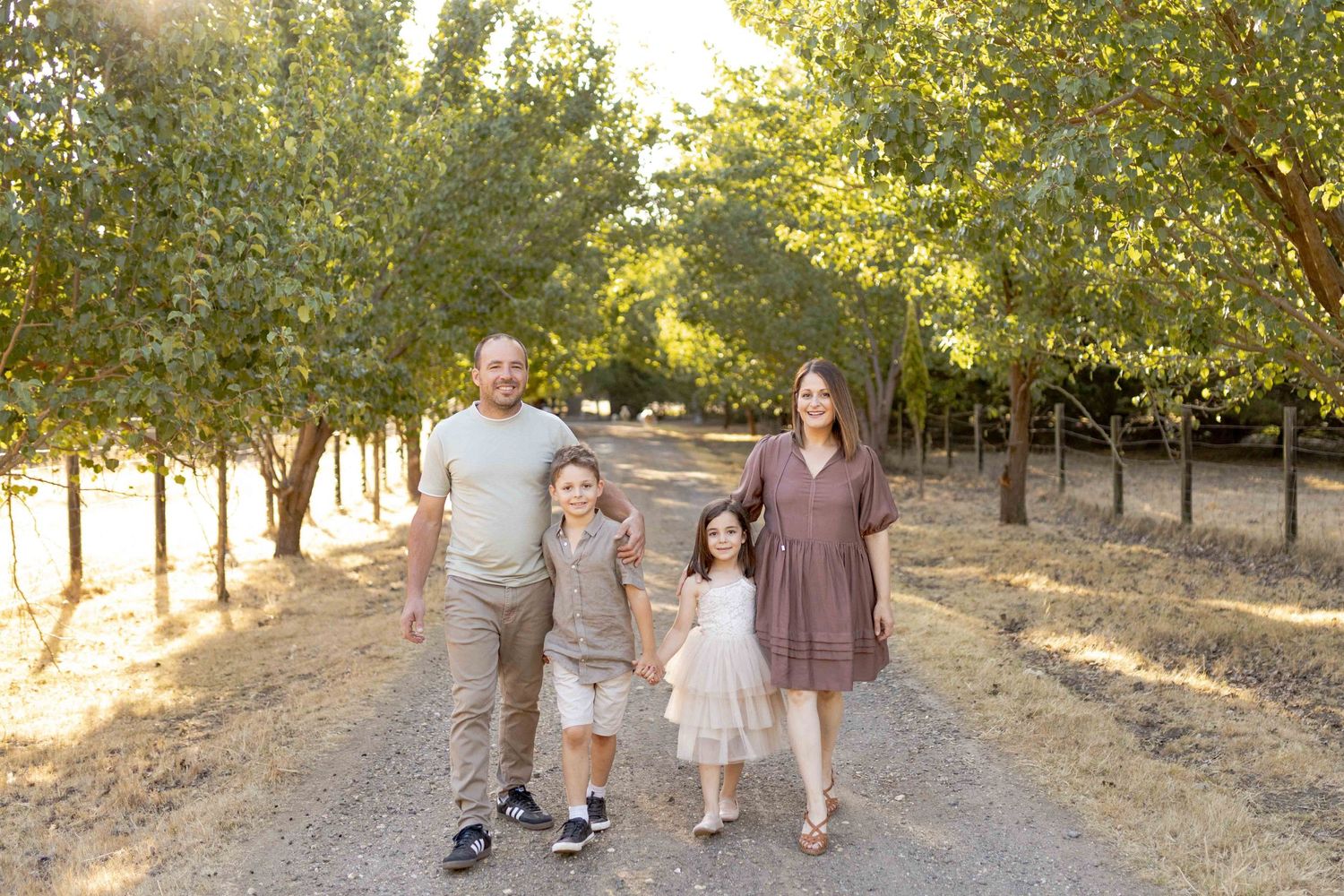 Family walking together in rows of trees comfortably  Outdoor at home family session Gisborne Melb Vic