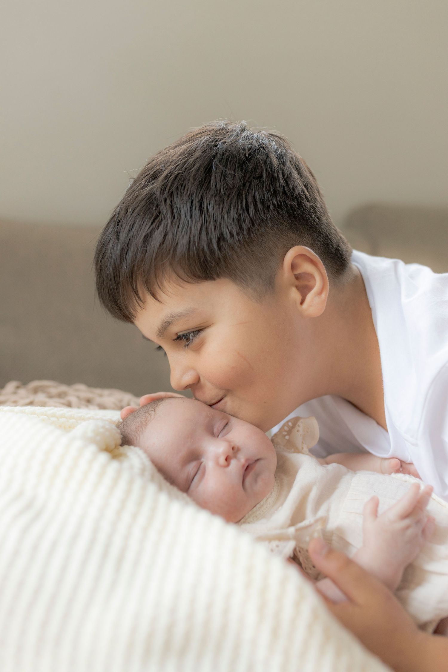 Big brother kissing baby sister on the head in a newborn photoshoot melbourne