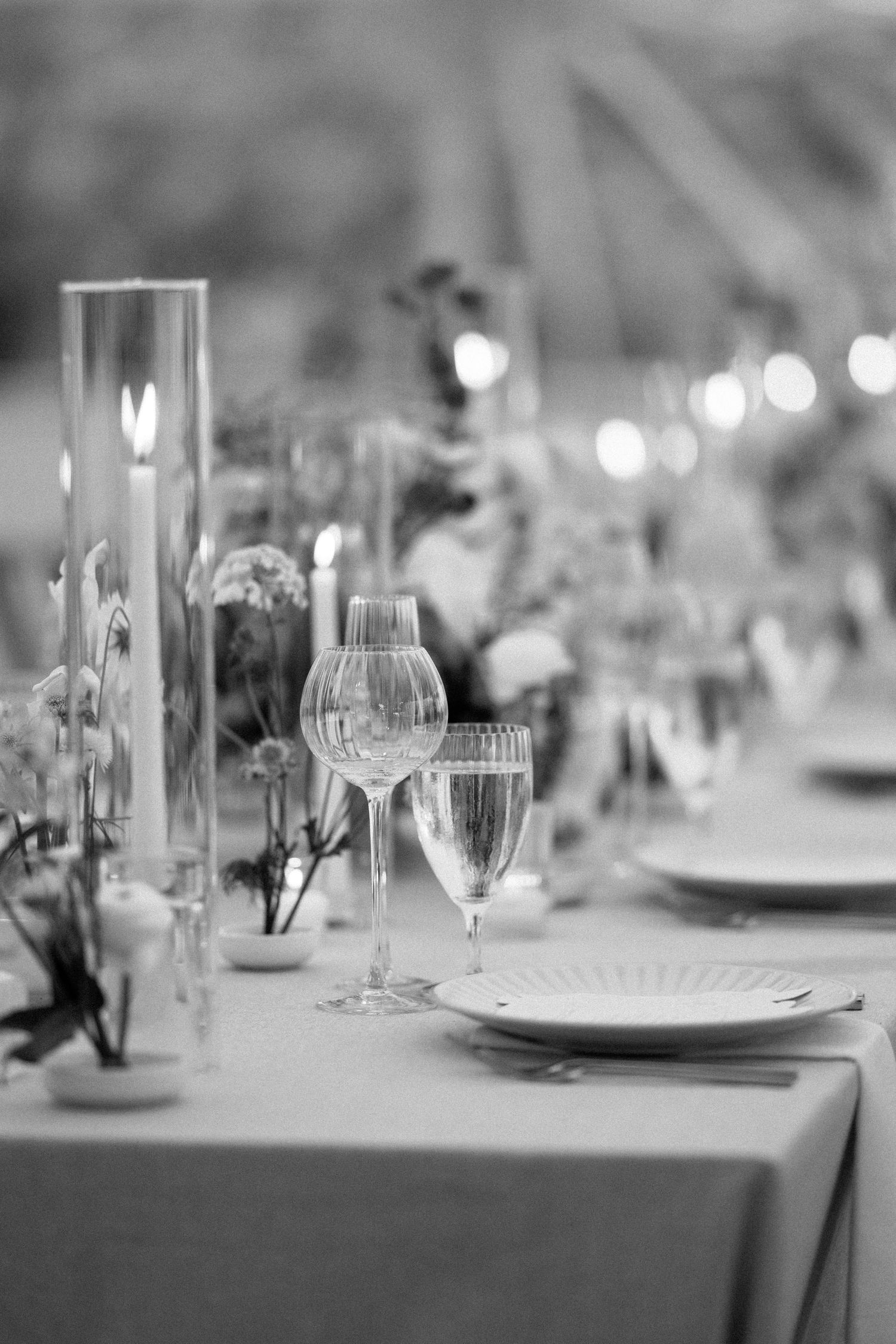 Elegant table settings at a formal event with crystal wine glasses and place settings in black and white photography.