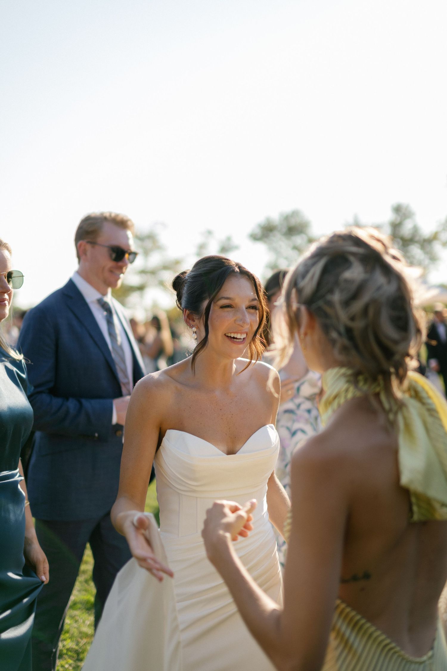 Outdoor wedding celebration with guests mingling in formal attire.