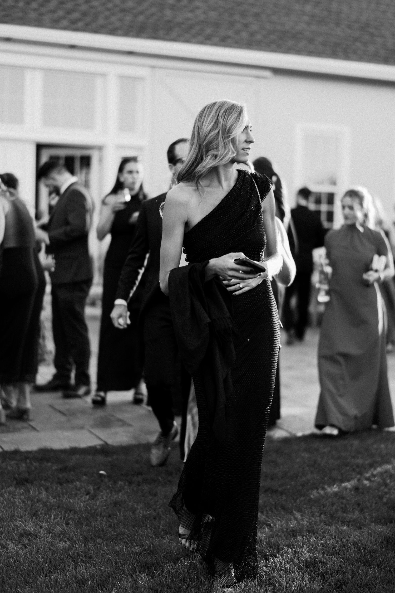 Elegant outdoor evening event with guests in formal attire enjoying a social gathering.