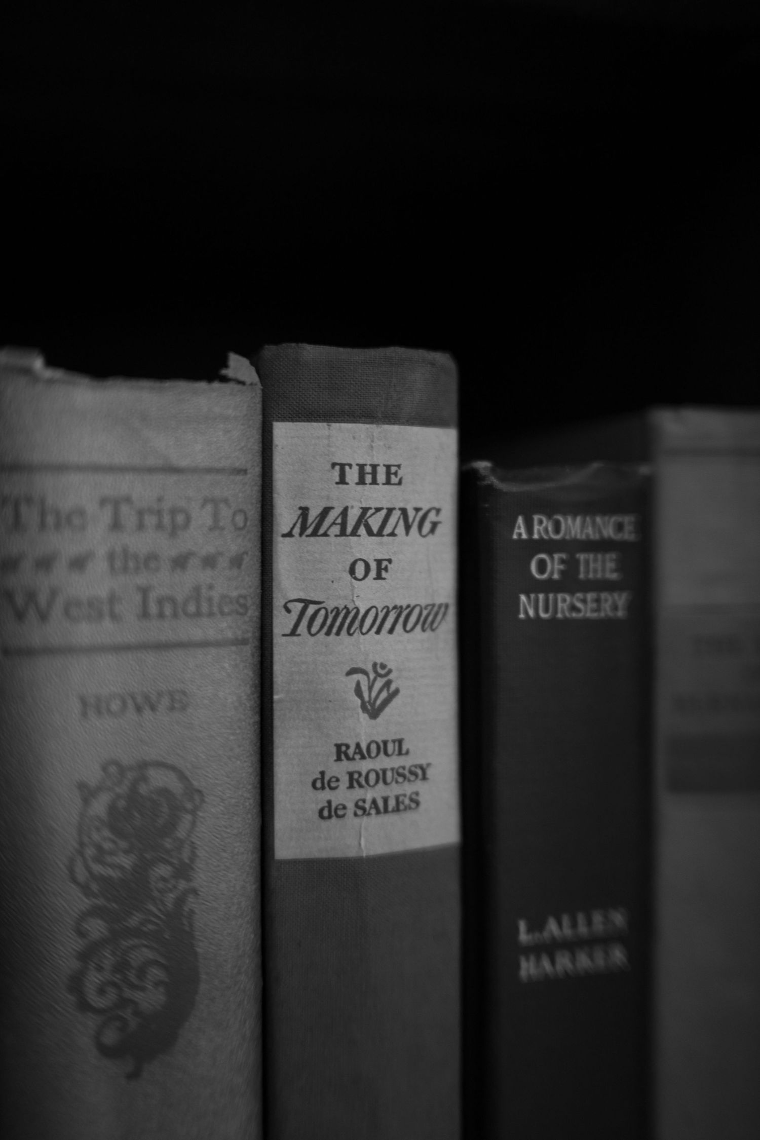 Black and white photo of vintage books on a shelf, including The Making of Tomorrow by Raoul de Roussy de Sales.