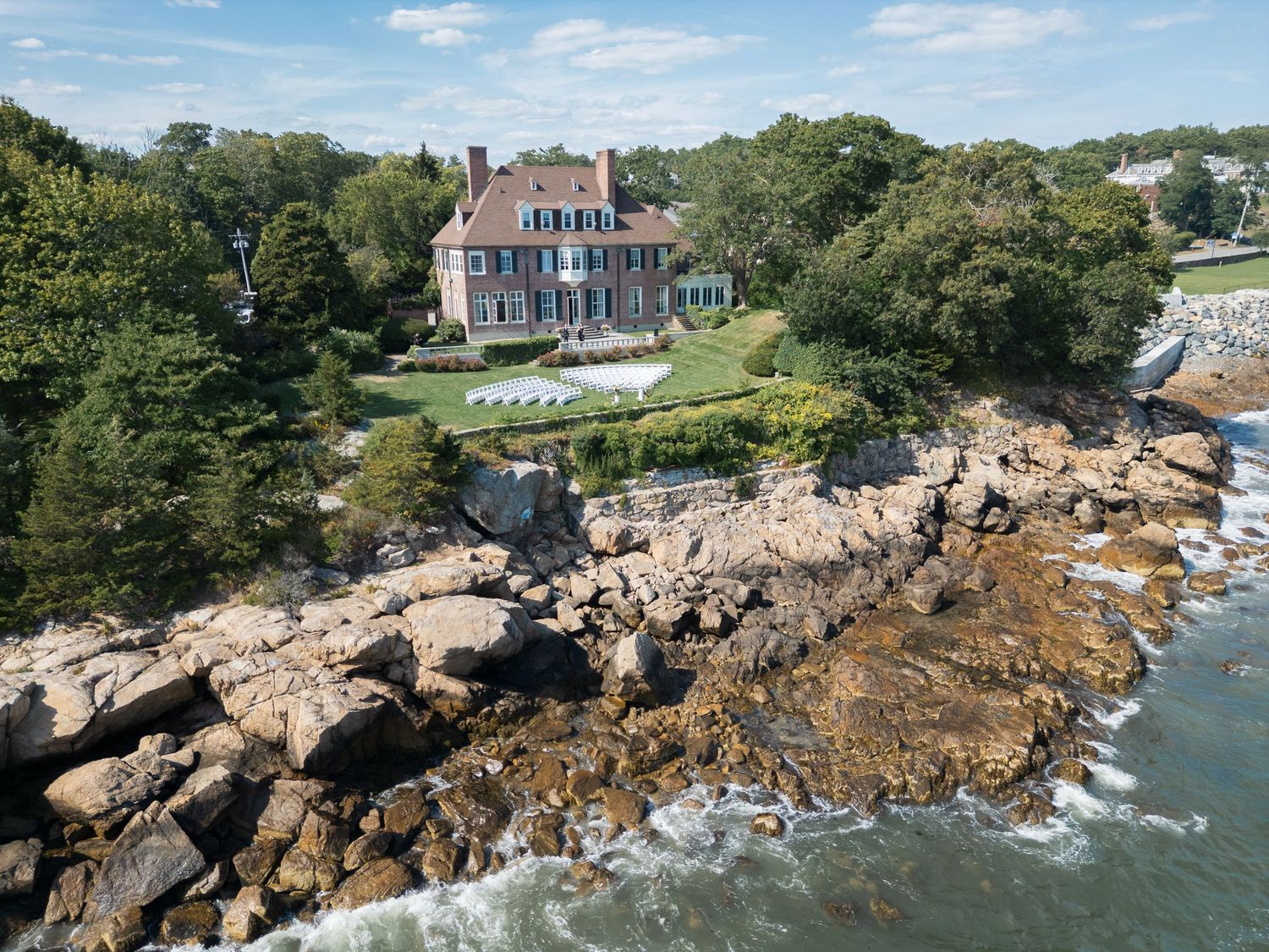 Scenic coastal views of rocky shoreline with historic New England homes perched along the rugged Maine coastline.