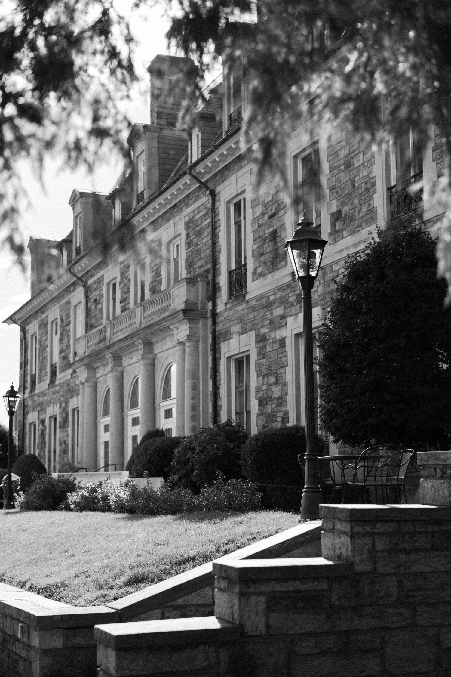 A black and white photo series showing different angles of a historic stone mansion with ornate architectural details.