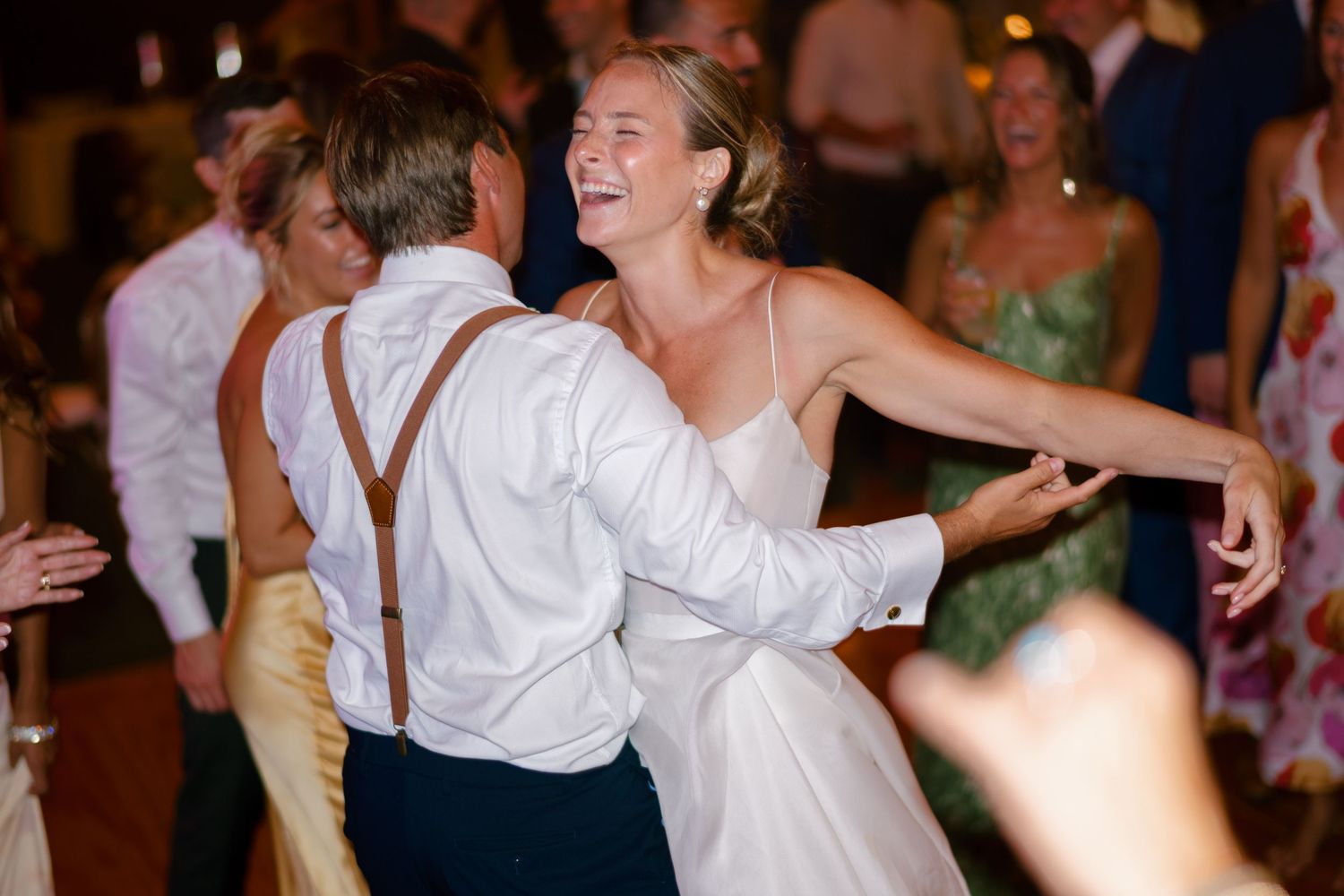 Bride and groom dancing together at wedding reception, smiling and embracing.
