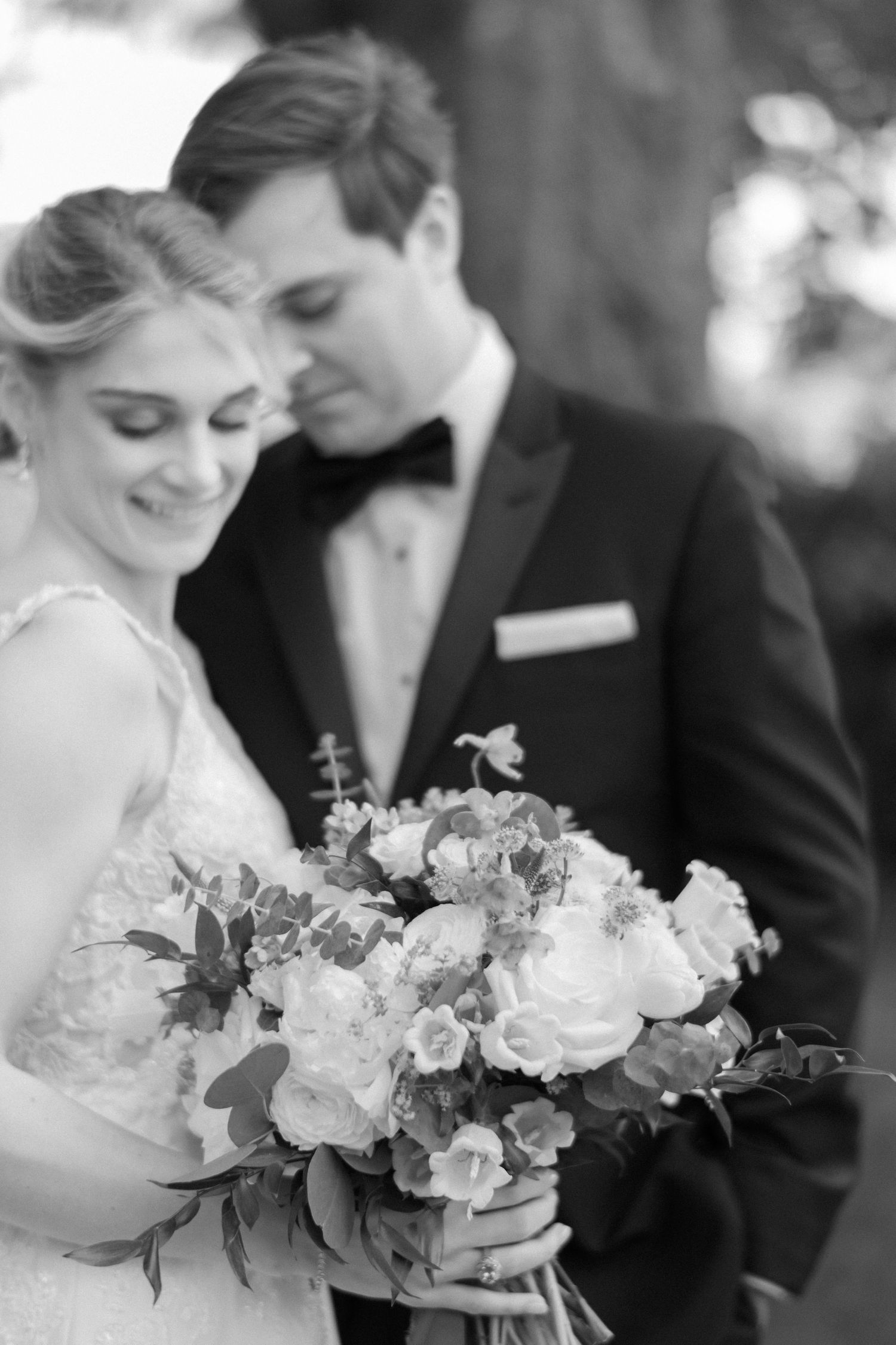 A tender moment with a bouquet of white flowers captured in black and white photography.