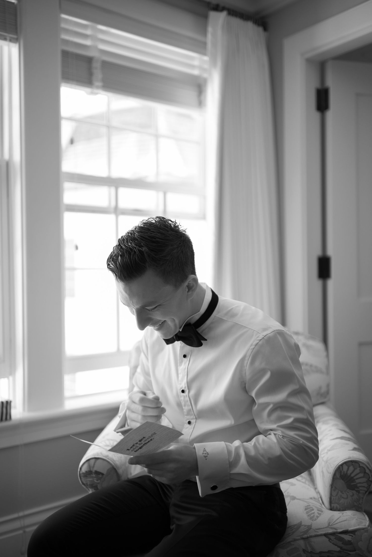 A person in a white dress shirt sits near windows in a black and white artistic photo series.