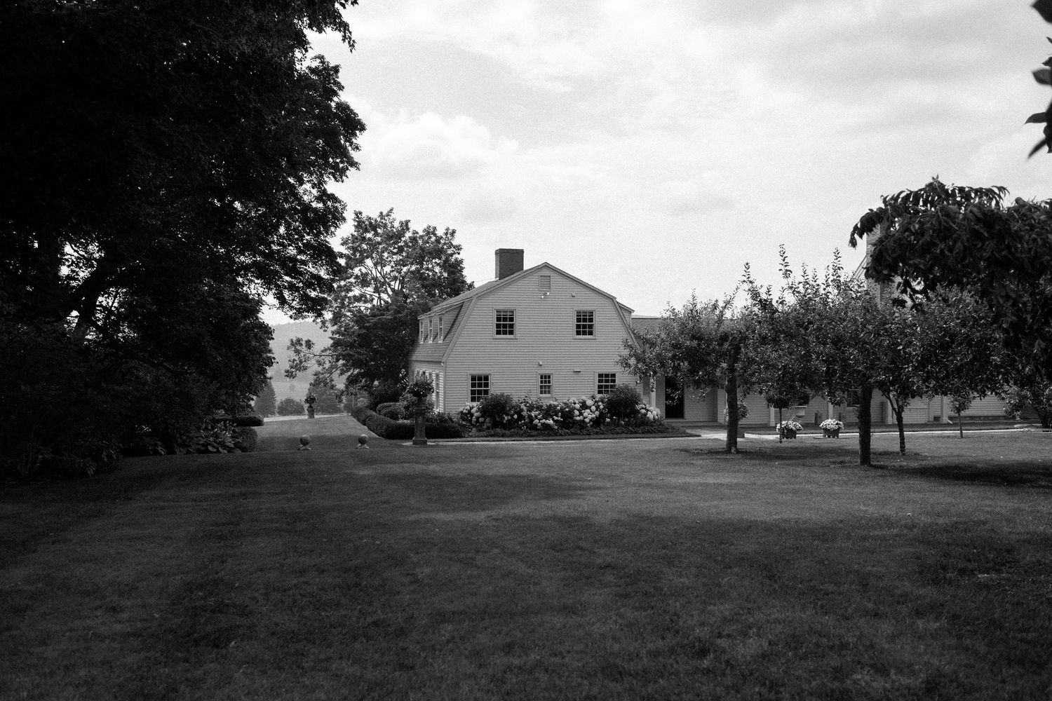 A series of black and white landscape photographs showing rural farmland with houses and trees in the distance.