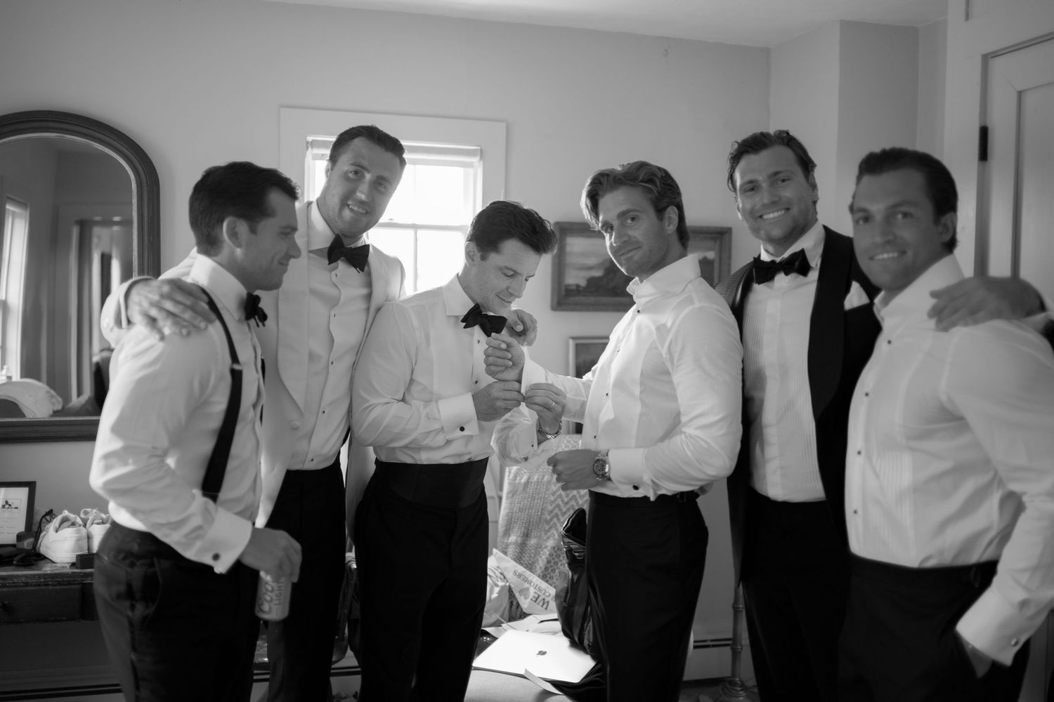 A series of black and white candid photos showing wedding party members getting ready in a room.