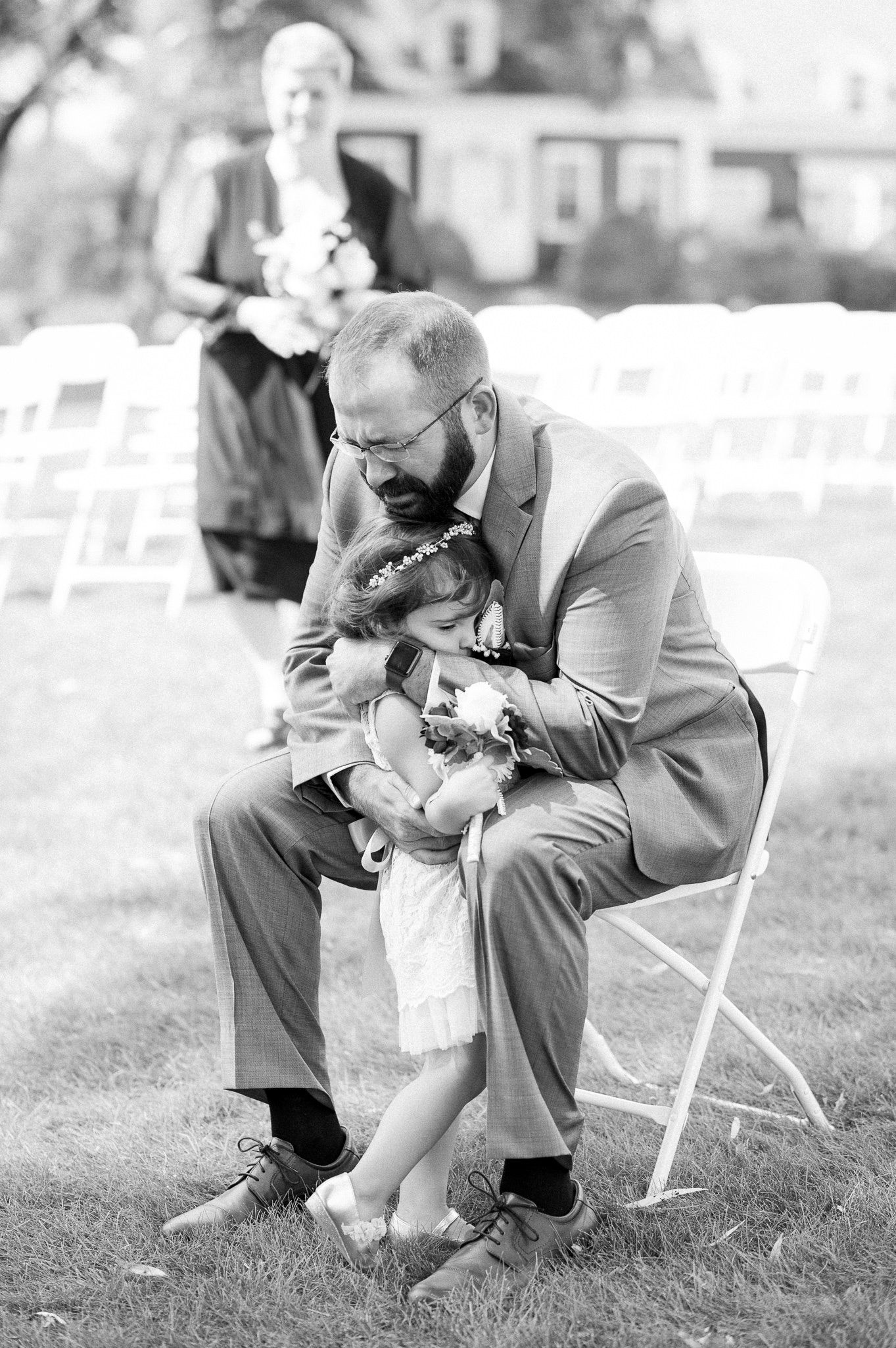 A tender moment between a father and child during an outdoor wedding ceremony.