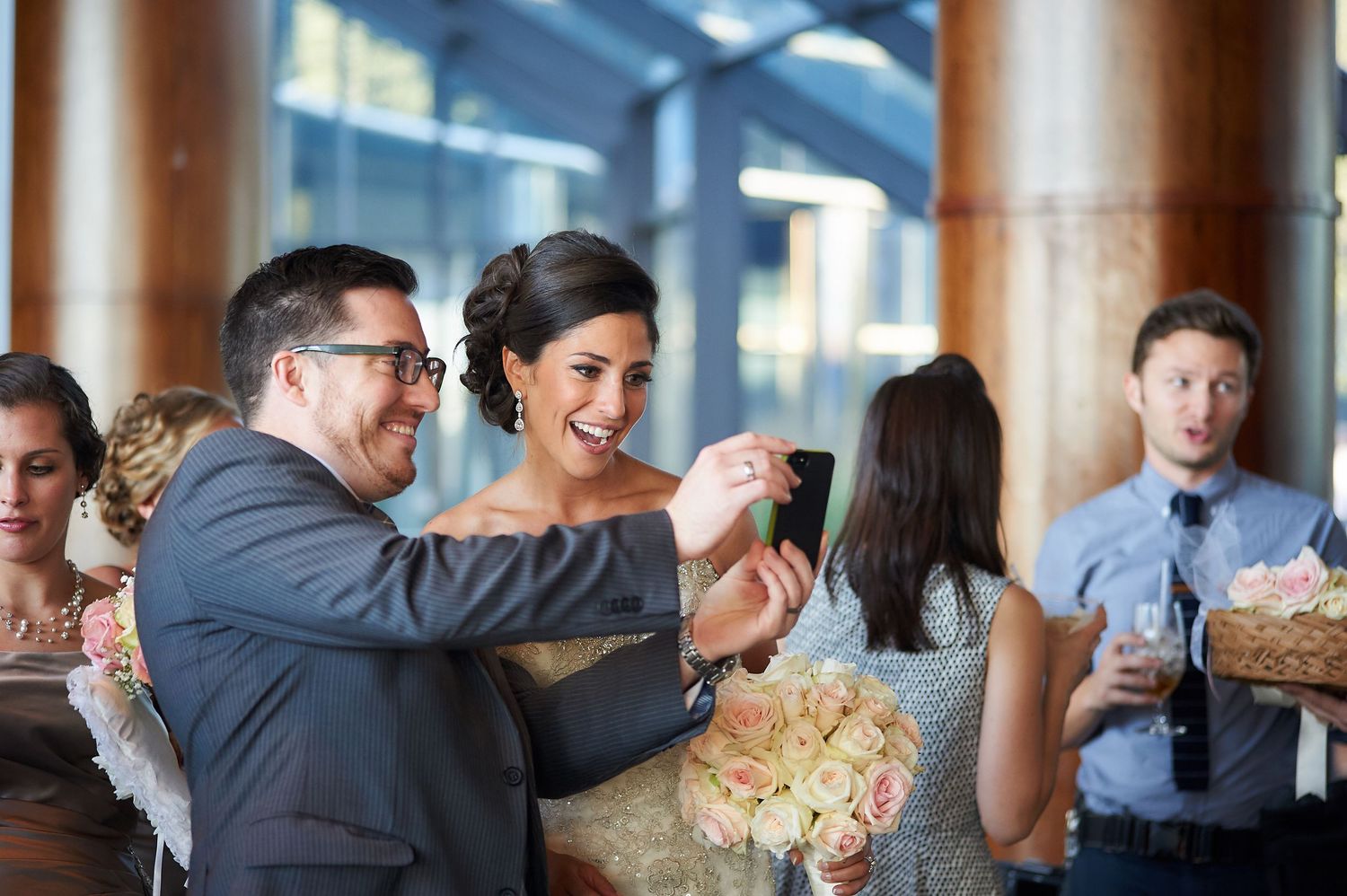 Wedding guests gather around buffet table sharing food and conversation at indoor reception.
