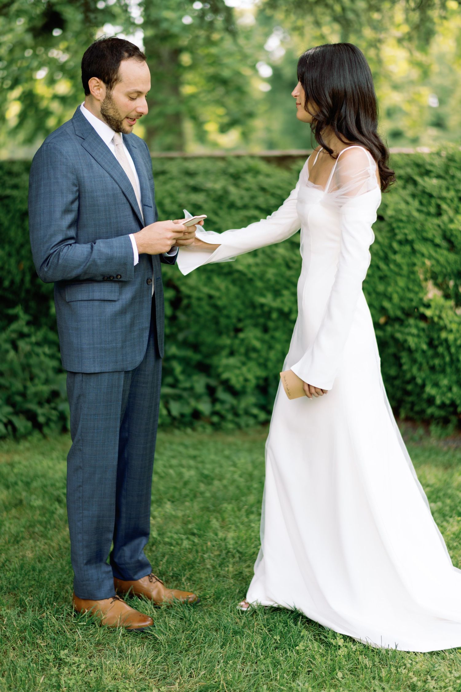 Couple exchanges rings during outdoor garden wedding ceremony.