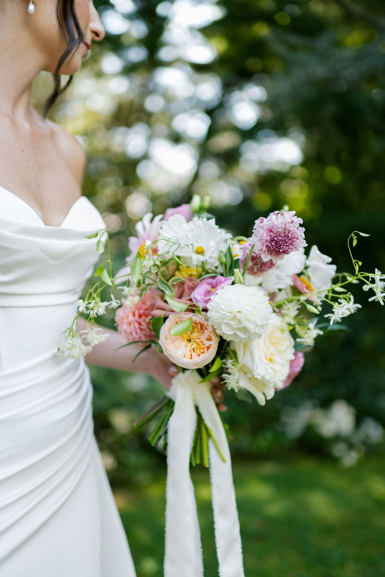 Beautiful wedding bouquet with pink and white flowers tied with flowing ribbons.