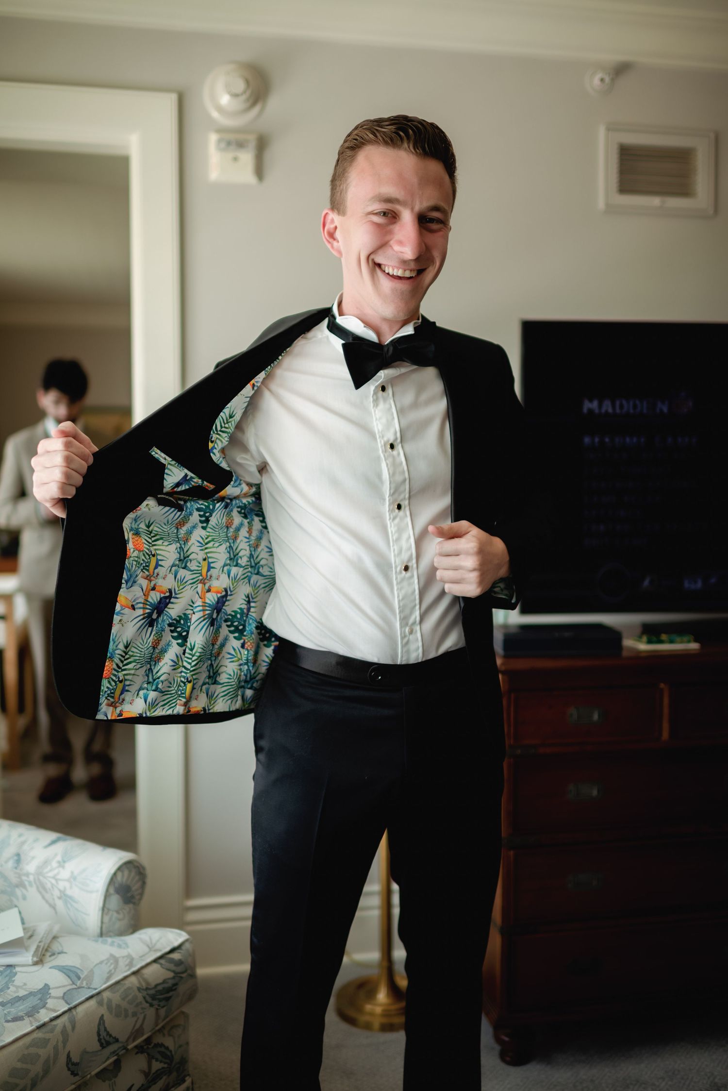 A person in a white dress shirt and black pants getting dressed for a formal occasion.
