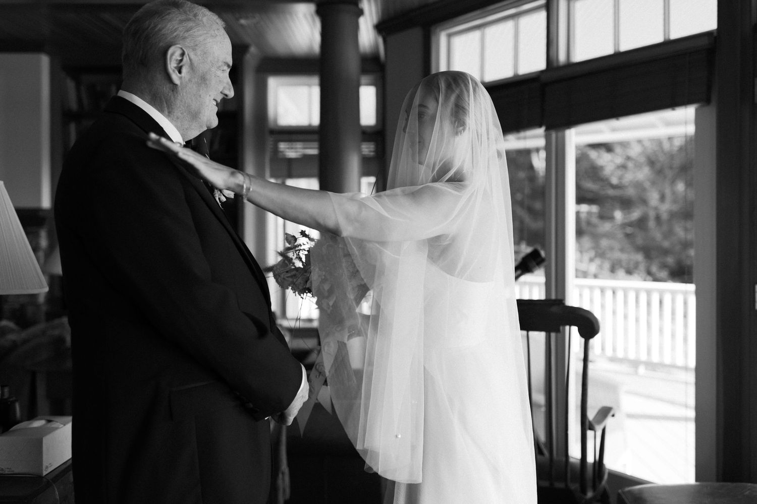 A touching moment between two people during wedding preparations in a sunlit room.