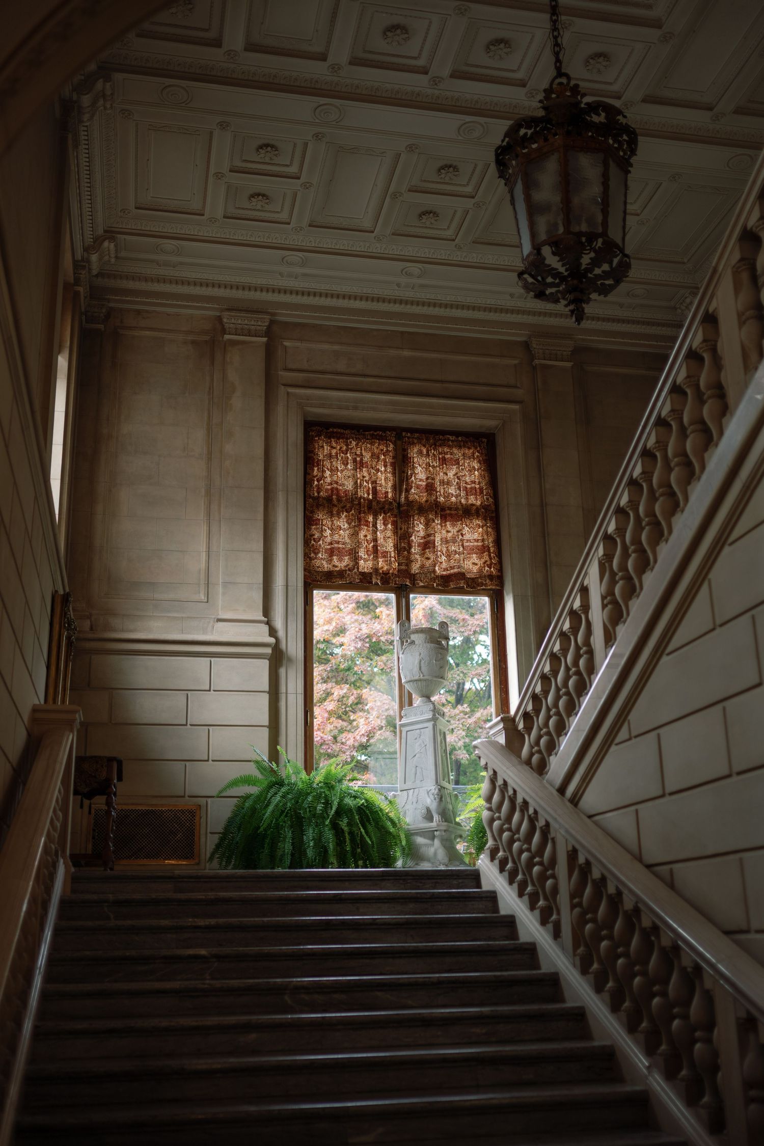 Elegant marble staircase with ornate railings and paneled walls in a historic mansion interior.