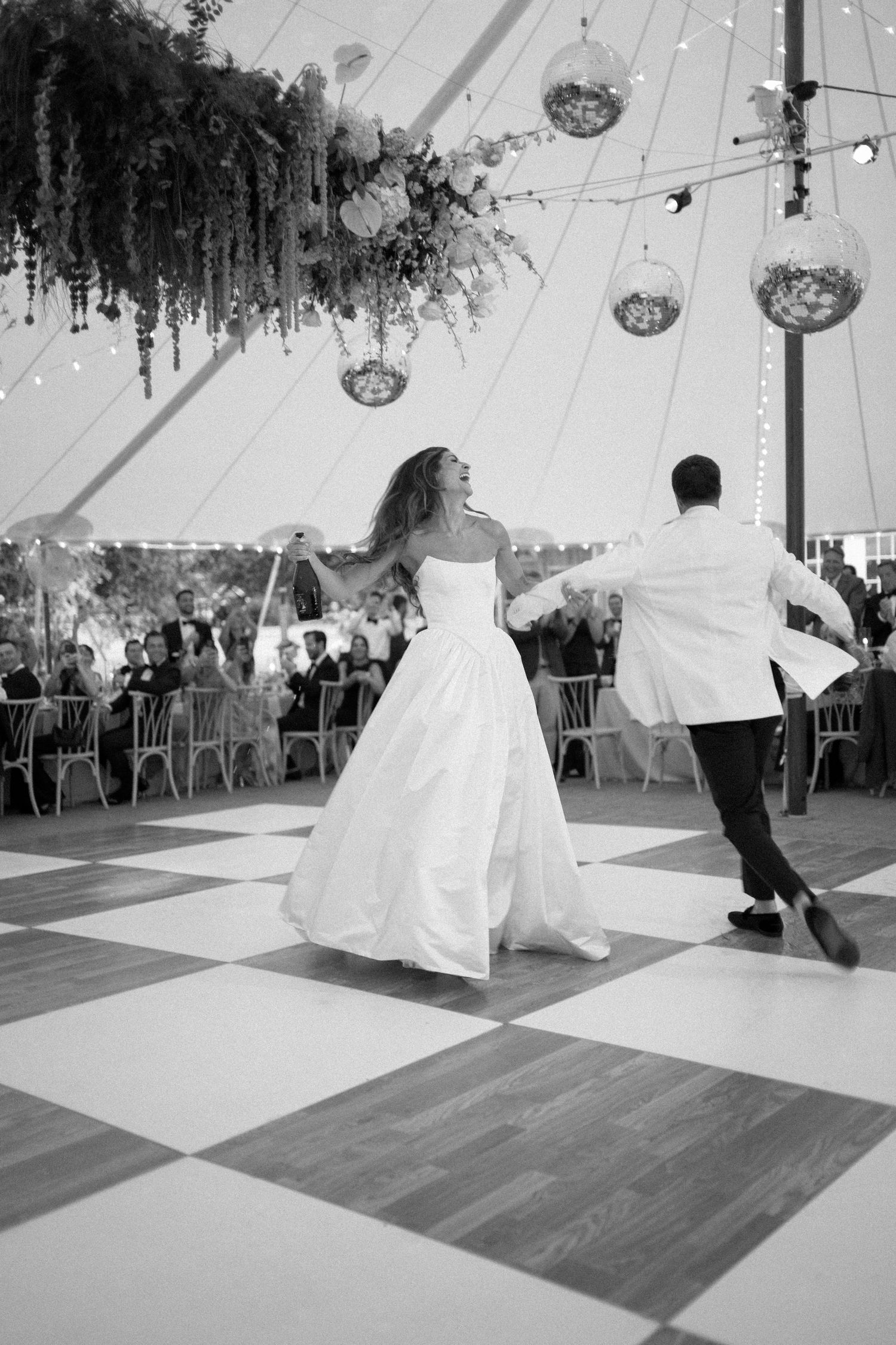 Black and white photo sequence of a couple performing their first dance at a wedding reception under hanging lights.