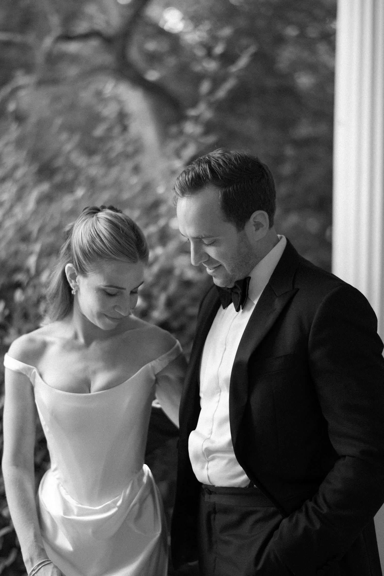 Black and white wedding photo series showing intimate moments between a bride in white dress and groom in tuxedo.