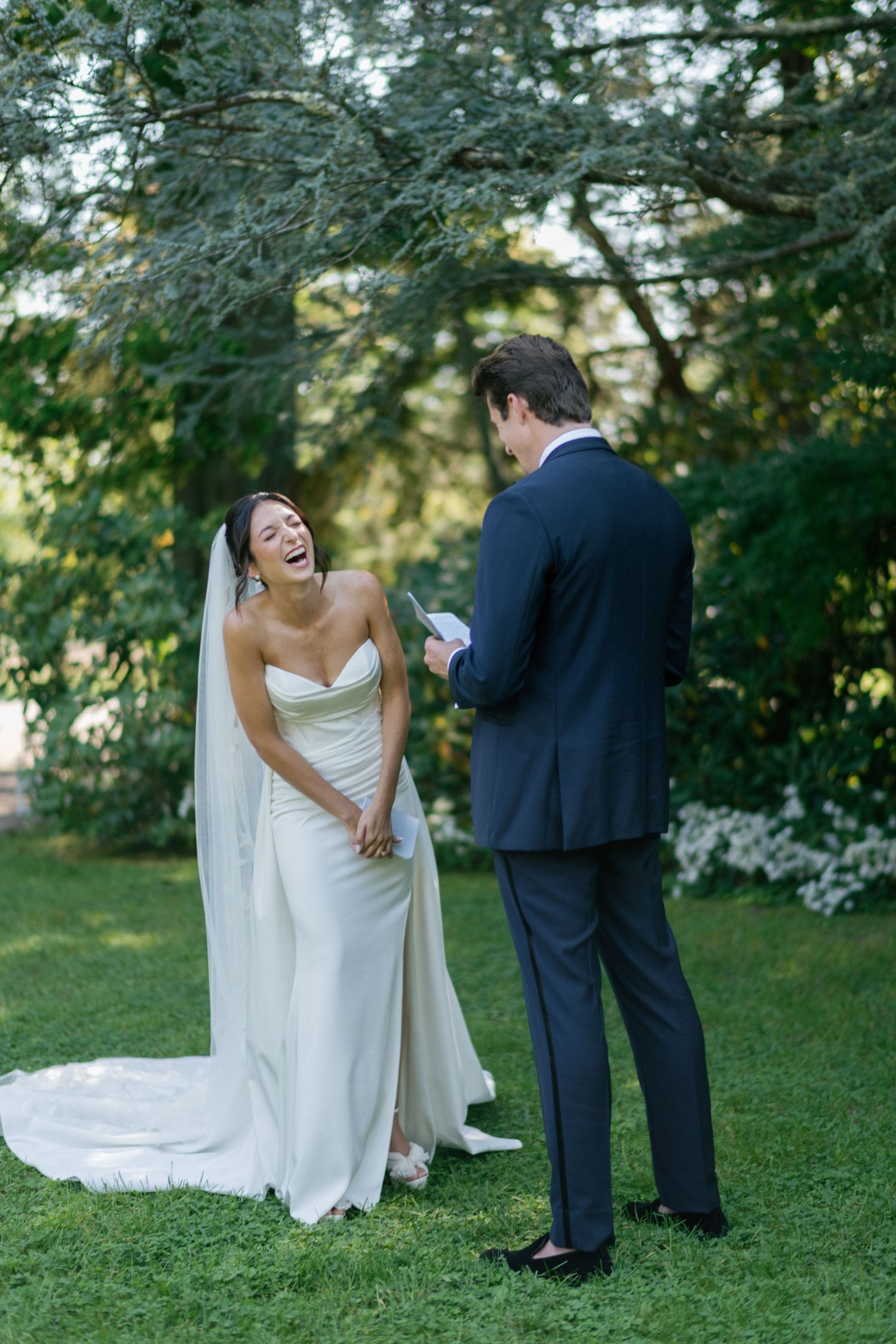 Couple shares a candid moment during their wedding vows in a garden setting.