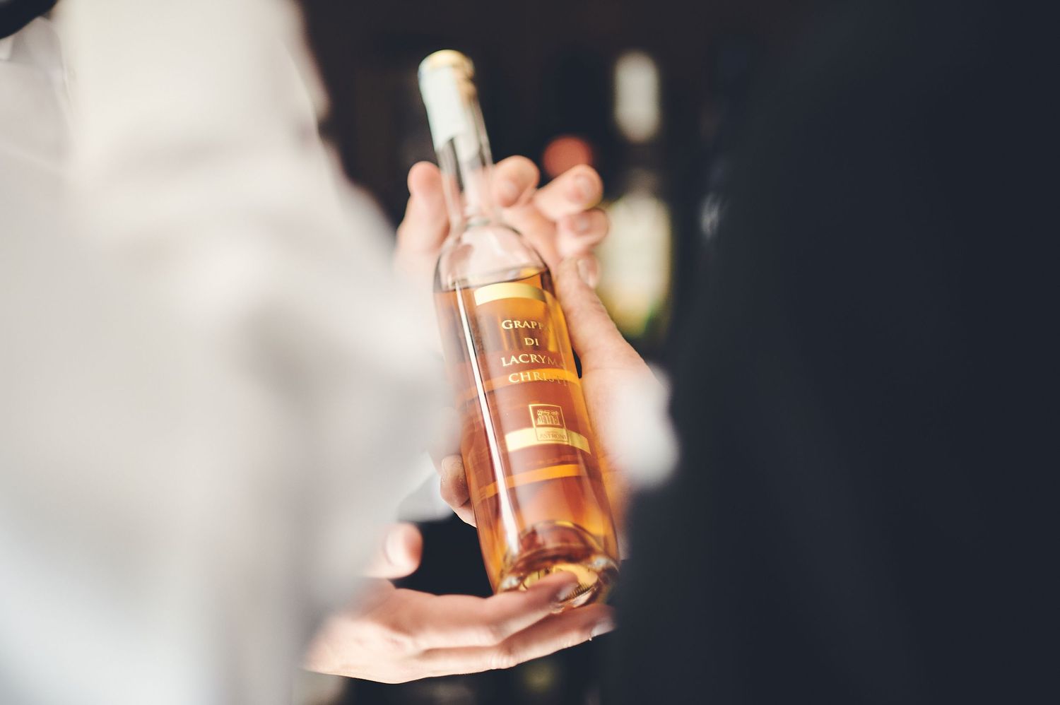 Close up of hands holding a bottle of champagne or wine at wedding celebration.