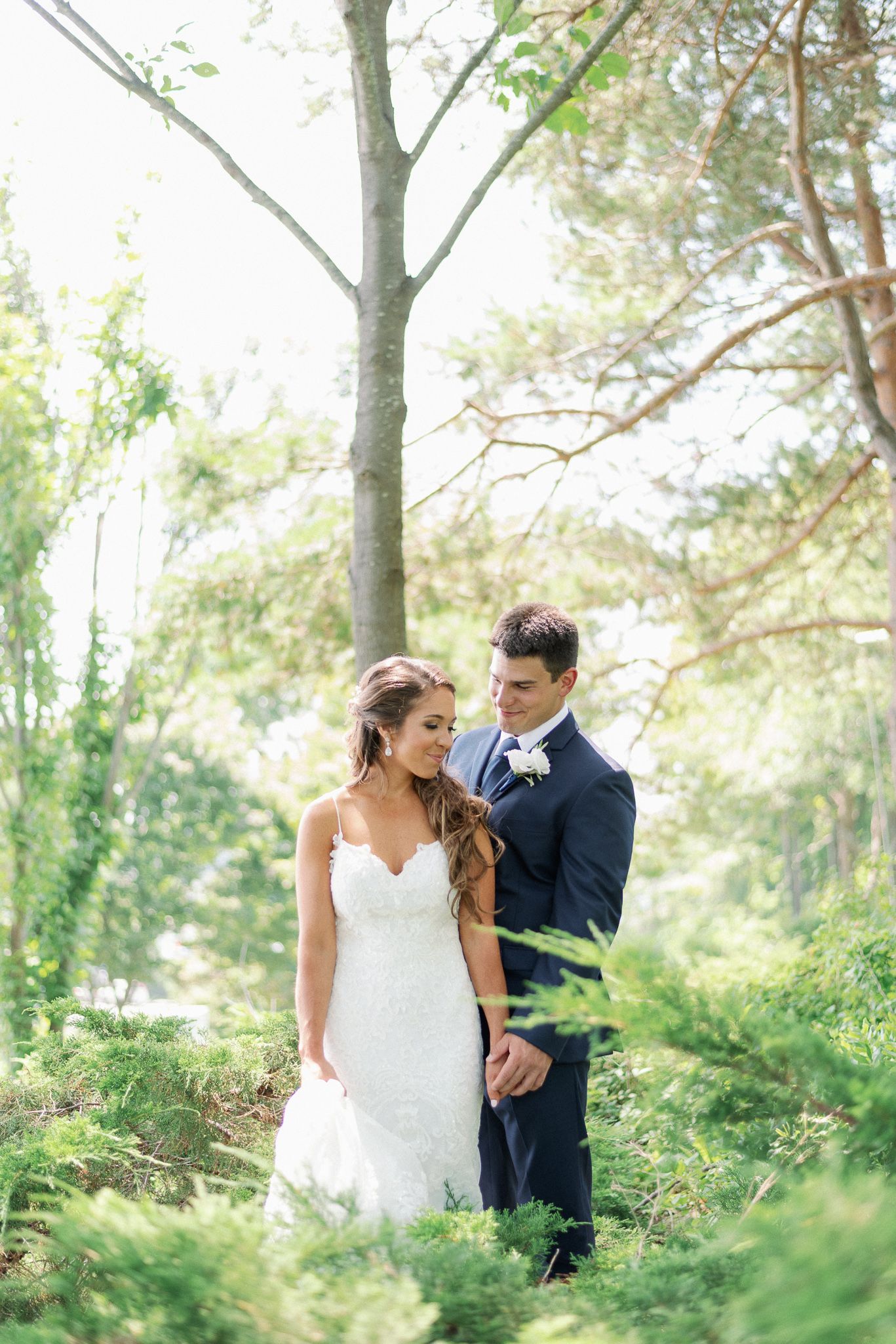 Romantic woodland wedding portrait with soft natural lighting and lush greenery.
