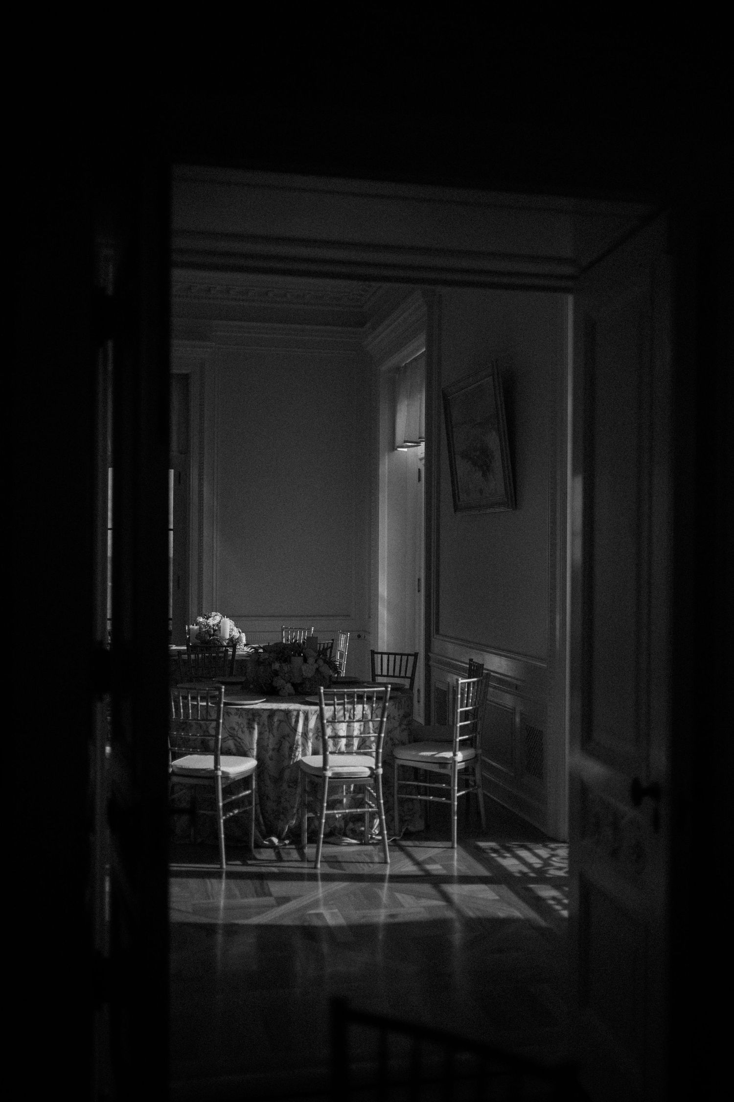 Dark moody interior scenes showing empty chairs and furniture casting dramatic shadows in black and white photography.