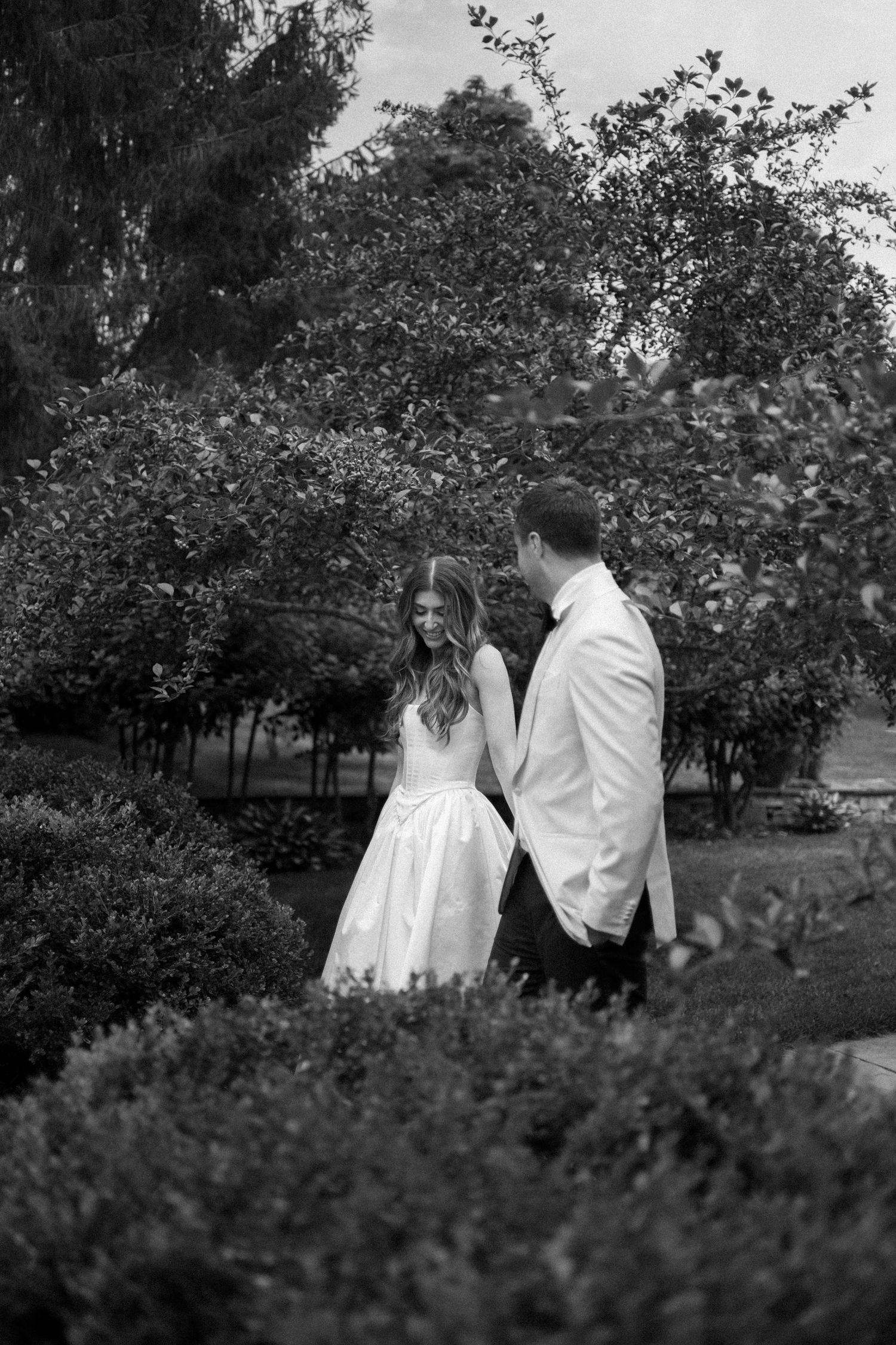 A romantic black and white photo sequence shows a couple walking together through a garden with lush trees and bushes.