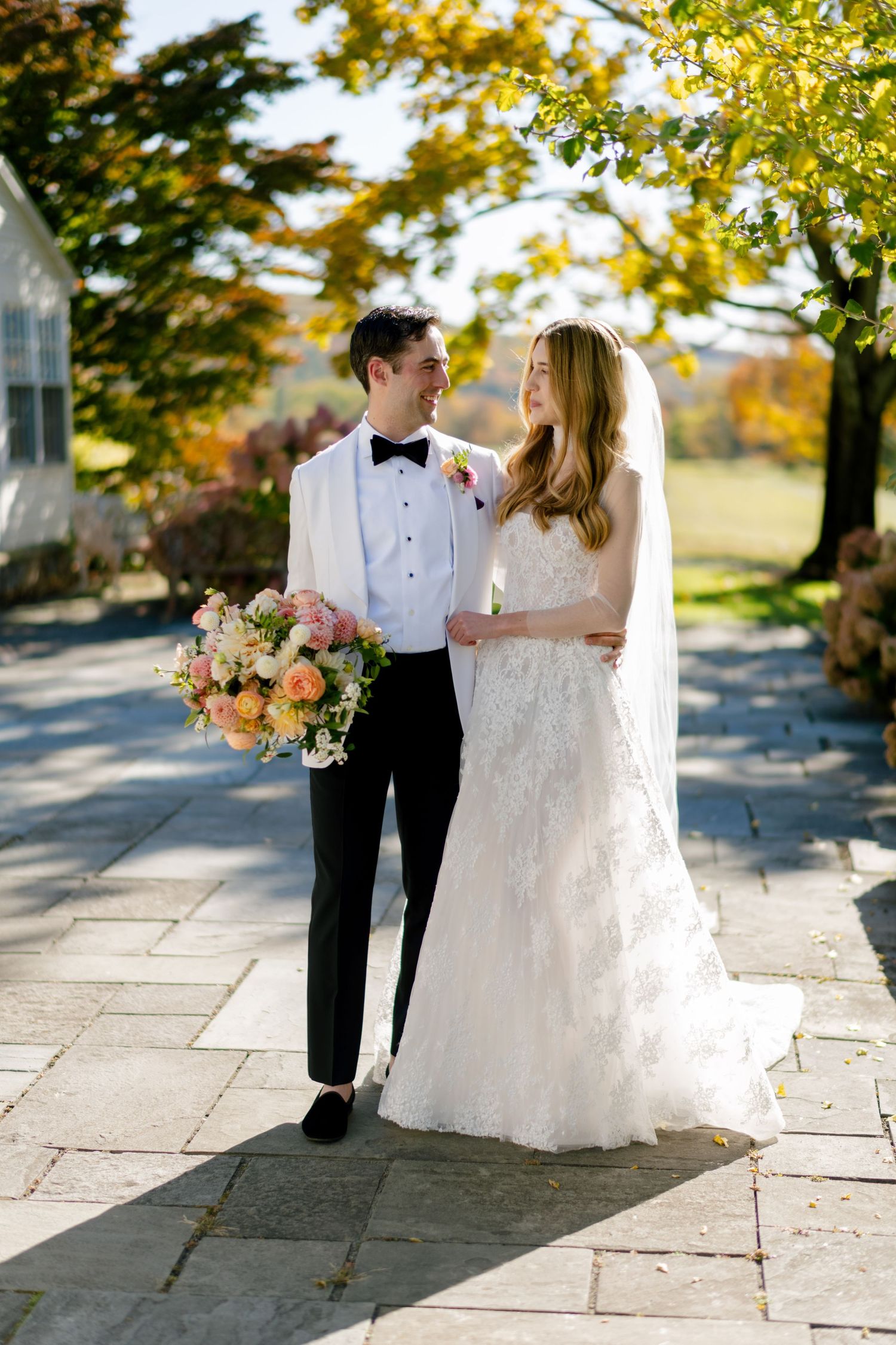Autumn wedding photo of couple walking on stone path with fall foliage.