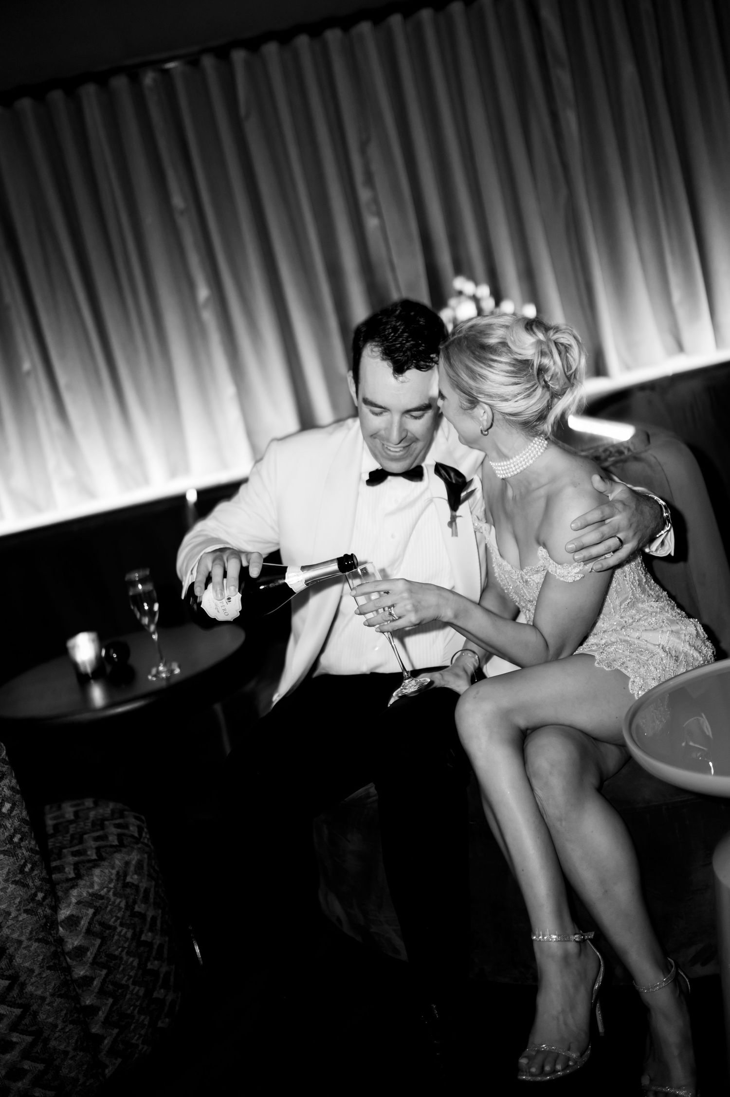 Artistic black and white photo of couple sharing drinks at evening celebration.