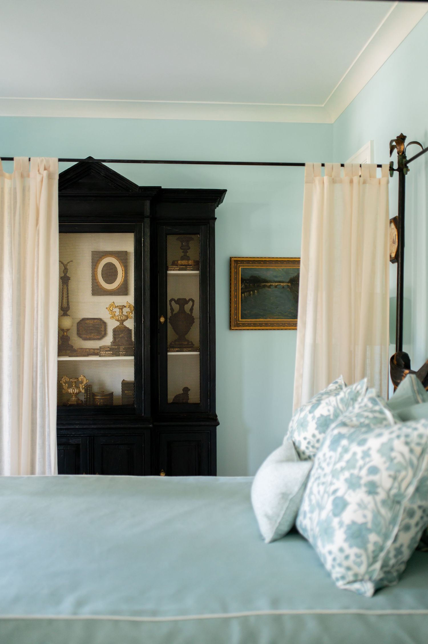 A series of identical bedroom photos showing light blue walls, white curtains, and decorative pillows on a bed.