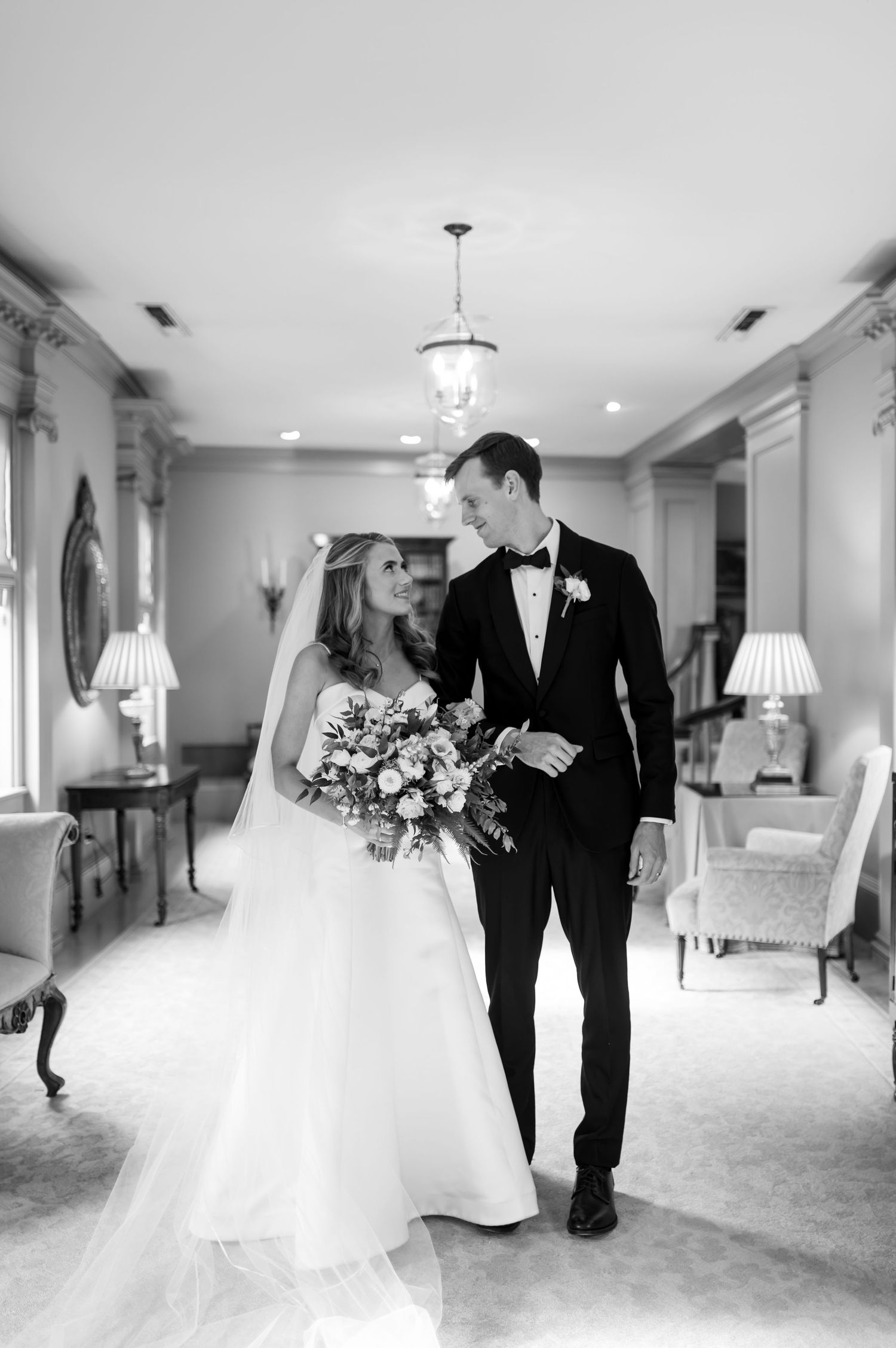 Black and white wedding photos in an elegant hallway with classic interior details.